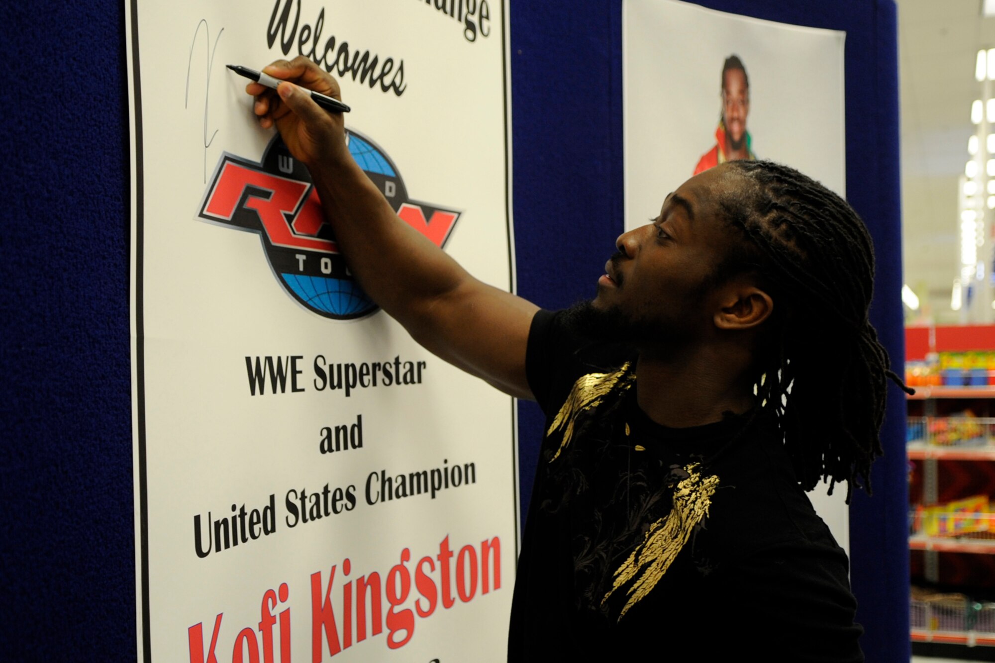 WWE Superstar and United States Champion Kofi Kingston, autographs a promotional poster after a “meet and greet the troops” event at the Base Exchange on Barksdale Air Force Base, La., May 10, 2013. Later that evening, Kingston defeated Cody Rhodes during a WWE Smackdown event at the Hirsch Memorial Coliseum in Shreveport, La. (U.S. Air Force photo by Master Sgt. Jeff Walston/Released)