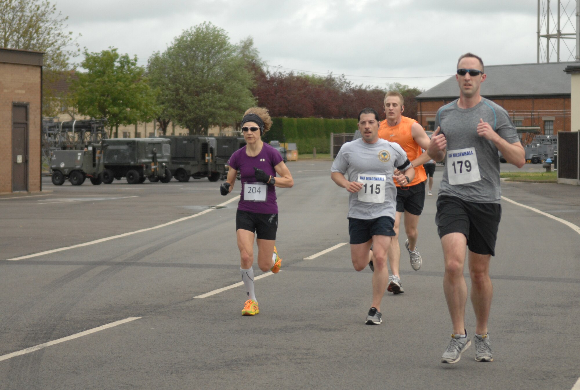 Team Mildenhall participants run past a water station during a half-marathon May 11, 2013, on RAF Mildenhall, England. Three water stations - set up along the path - kept runners hydrated during the 13.1 mile race. (U.S. Air Force photo by Airman 1st Class Dillon Johnston/Released)