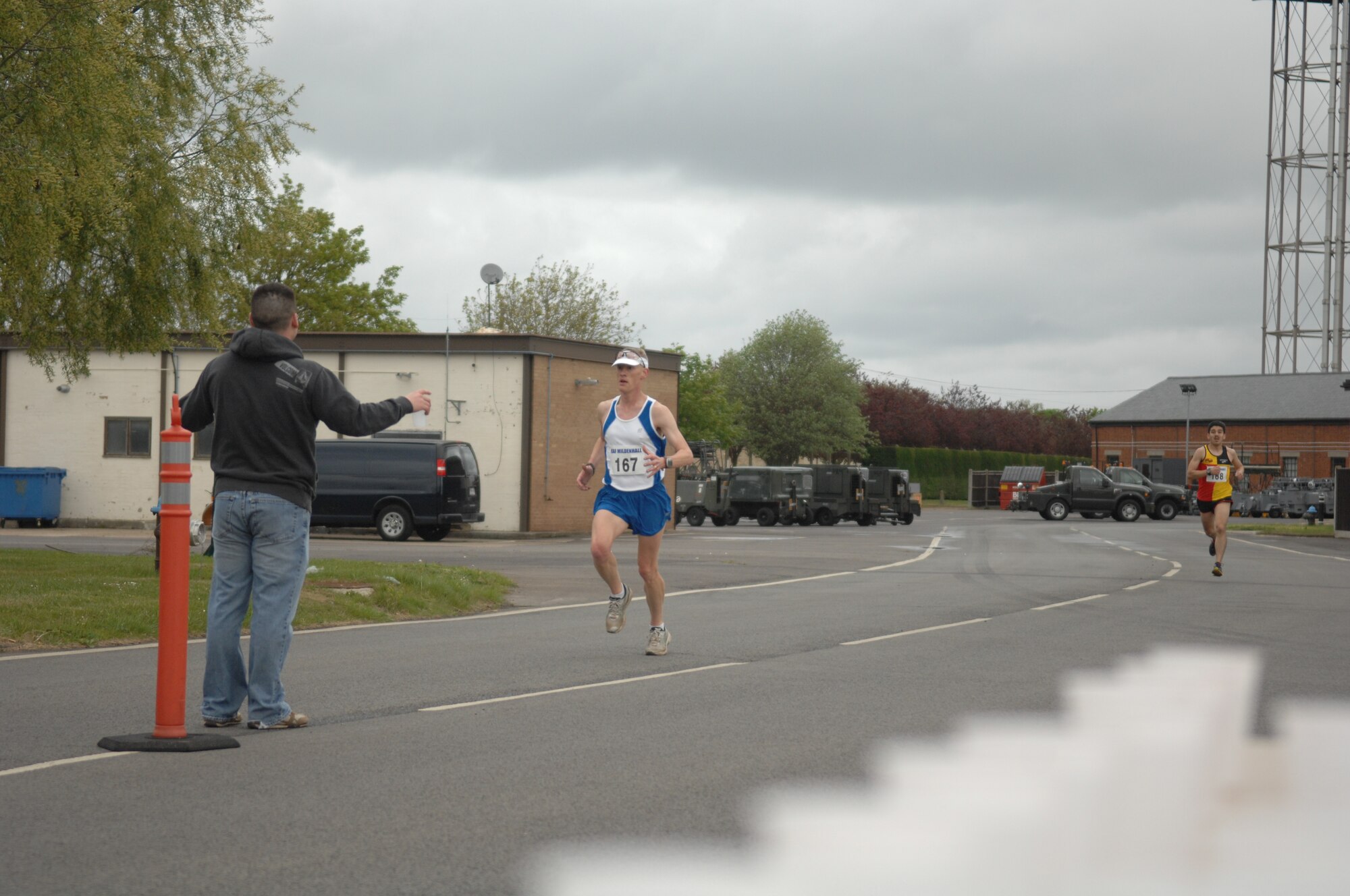 Center, Lt. Col. Christopher Bennett, 100th Operations Support Squadron commander, leads the pack as he runs past a water station during a half-marathon May 11, 2013, on RAF Mildenhall, England. Bennett, an avid runner, ran more than 800 days straight leading up to the half-marathon. (U.S. Air Force photo by Airman 1st Class Dillon Johnston/Released)