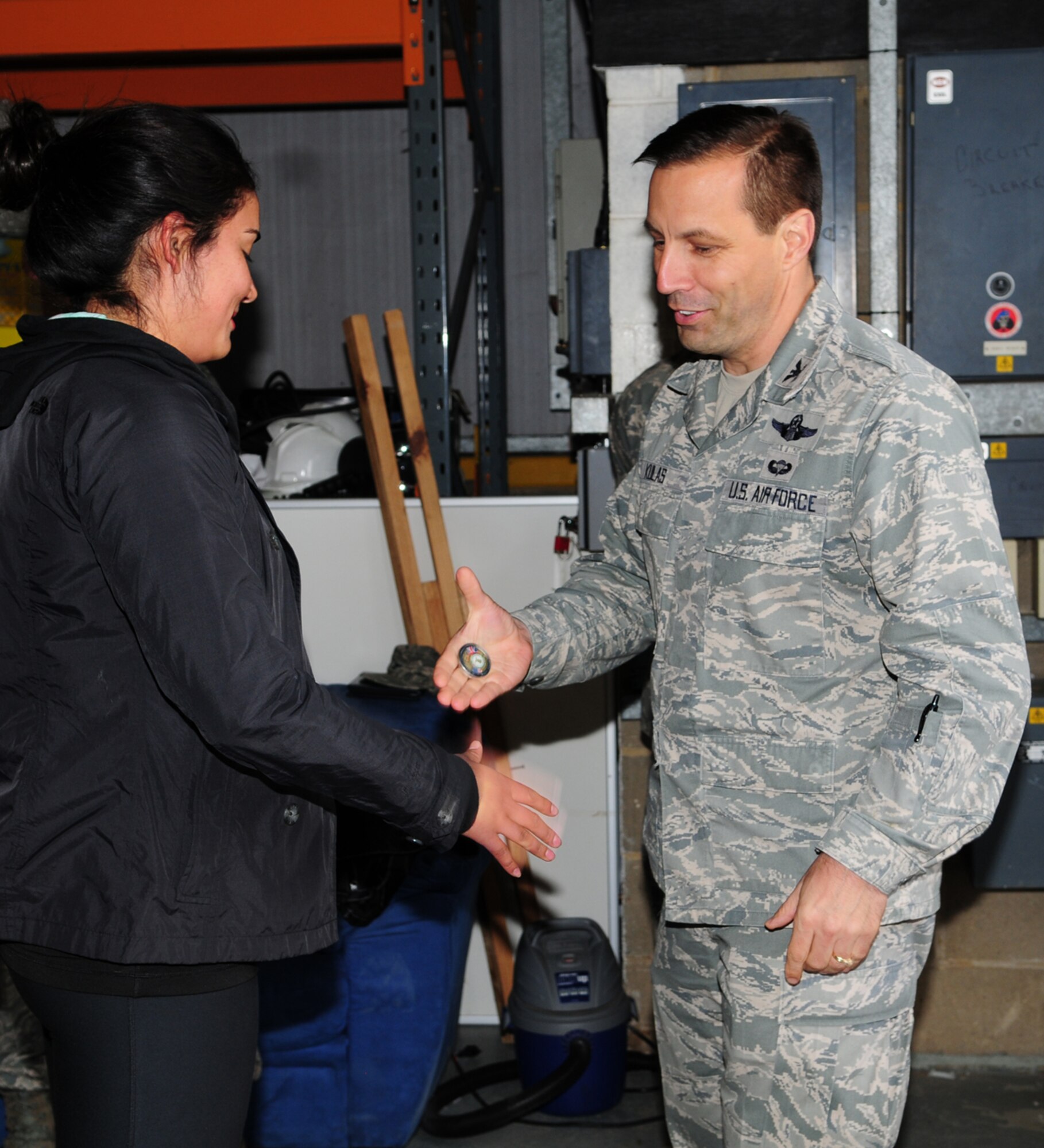 From left, Airman 1st Class Karla Rosas, 100th Security Forces Squadron member from Chicago, receives a commander’s coin from Col. Christopher Kulas, 100th Air Refueling Wing commander, May 9, 2013, after she returned home to RAF Mildenhall, England, from a six-month deployment. Rosas was coined by Kulas on behalf of Brig. Gen. Steven Shepro, 438th Air Expeditionary Wing commander, after she won the 438th AEW Airman of the Quarter Award at her deployed location. (U.S. Air Force photo by Karen Abeyasekere/Released)