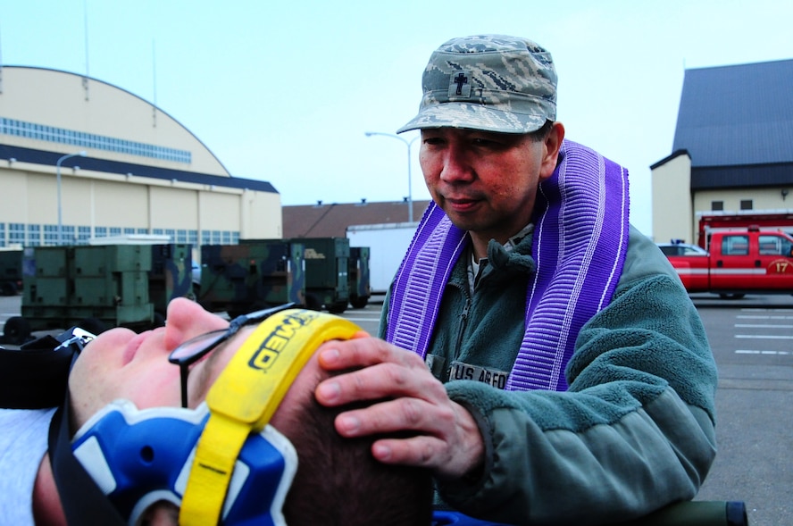 U.S. Air Force Chaplain (Capt.) Antionio Rigonan, 35th Fighter Wing chaplain, provides spiritual comfort to simulated victims during a base Emergency Management Exercise at Misawa Air Base, Japan, May 13, 2013. Base chaplains are skilled in crisis counseling and assisting members experiencing unfortunate circumstances.  (U. S. Air Force photo by Staff Sgt. April Quintanilla)