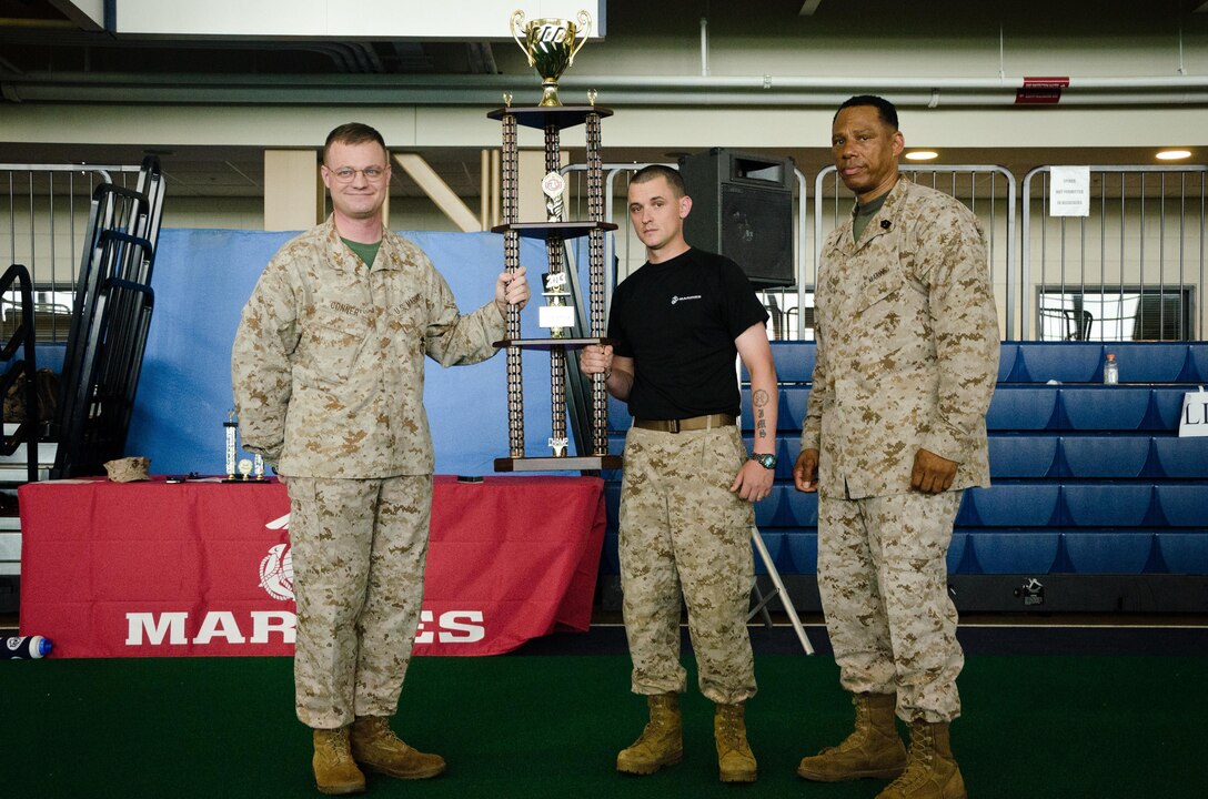 Major Christopher S. Conner, the commanding officer of Marine Corps Recruiting Station Baltimore, and Sergeant Maj. Brian Taylor, the sergeant major for RS Baltimore, present Staff Sgt. Josef M. Surunis, a recruiter from Recruiting Sub-Station Glen Burnie, with a trophy representing first place in the field meet during RS Baltimore’s statewide pool function at the United States Naval Academy, May 11. 