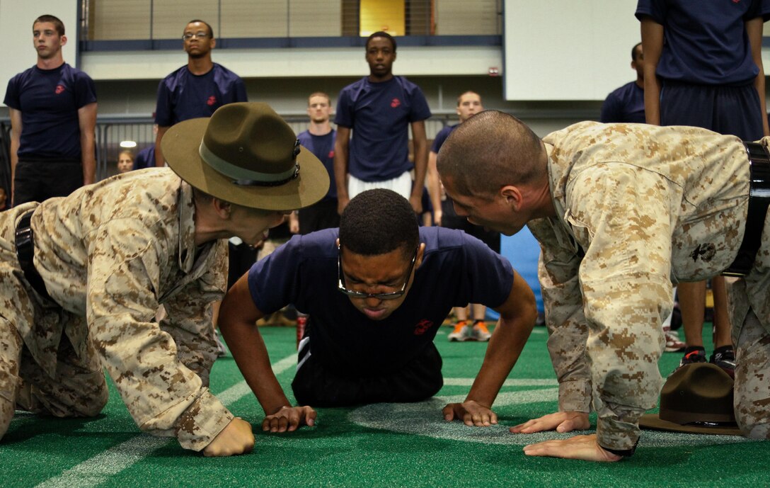 Gunnery Sgt. Tony S. Kimmanee (left) and Gunnery Sgt. Roberto Barba Jr., both drill instructors at the United States Naval Academy, encourage a poolee from Marine Corps Recruiting Station Baltimore to do more pushups during RS Baltimore’s statewide pool function at the USNA, May 11. 