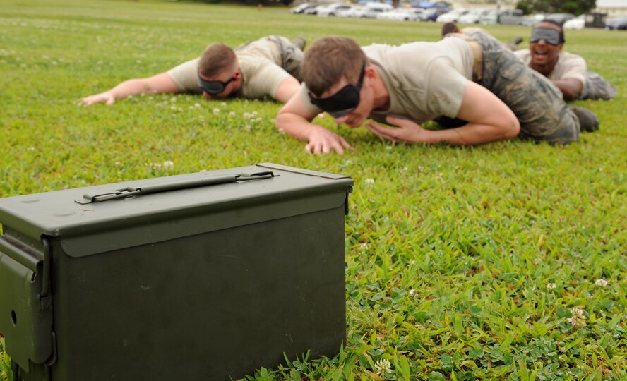 Members of the 18th Security Forces Squadron low crawl towards an ammo box on Kadena Air Base, Japan, May 14, 2013. The members were blind folded, spun around for a minute, and instructed find the ammo box by communicating and listening for the banging on the box by an instructor. (U.S. Air Force photo by Airman 1st Class Keith A. James/Released)