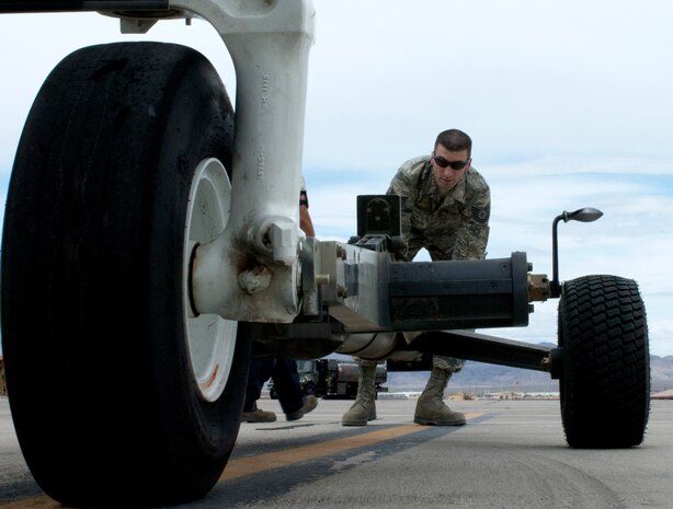 Tech Sgt. Thomas Puckett, 757th Aircraft Maintenance Squadron flightline expediter, pushes a towbar  up to the landing gear of an A-10 Thunderbolt II May 9, 2013, at Nellis Air Force Base, Nev. The towbar was used to attach the aircraft to ground equipment which then transported the aircraft back to the Thunder aircraft maintenance unit from base operations. (U.S. Air Force photo by Airman 1st Class Joshua Kleinholz)