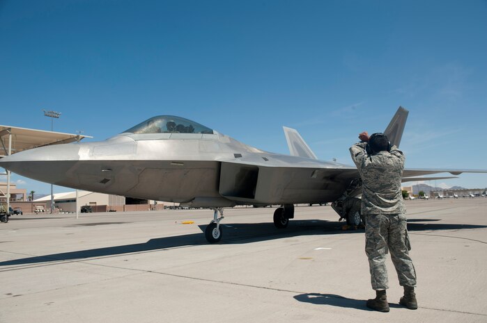Senior Airman Juan Vela, 57th Aircraft Maintenance Squadron crew chief, directs an F-22A Raptor piloted by Col. Alex Grynkewich, 57th Wing vice commander, to its parking spot at the conclusion of his “fini-flight” May 10, 2013, at Nellis Air Force Base, Nev. Grynkewich has served as the wing’s vice-commander since June 2012. (U.S. Air Force photo by Staff Sgt. Michael Charles) 