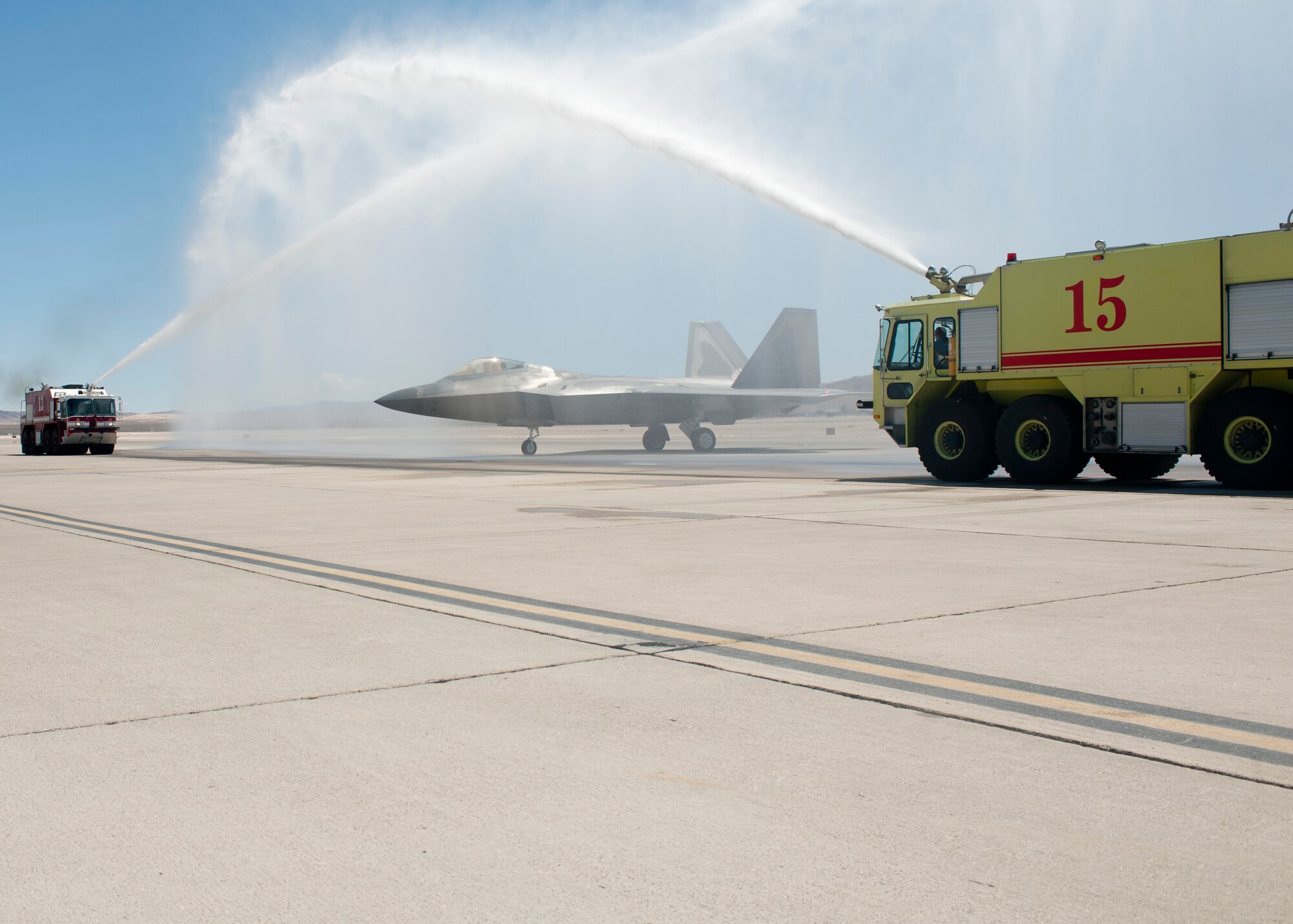 Firetrucks from the 99th Civil Engineer Squadron fire department spray down an F-22A Raptor flown by Col. Alex Grynkewich, 57th Wing vice commander, after his “fini- flight” May 10, 2013, at Nellis Air Force Base, Nev. Grynkewich’s next assignment is commander of  the 53rd Wing at Eglin AFB, Fla. (U.S. Air Force photo by Staff Sgt. Michael Charles) 
