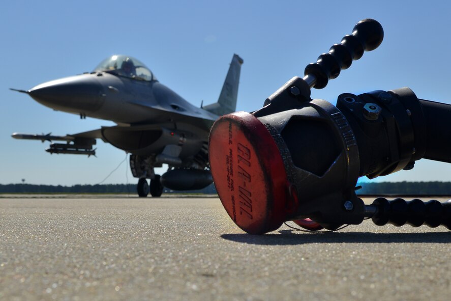 A gas hose and a F-16 Falcon Fighter are photographed during a hot pits refueling, Shaw Air Force Base, S.C., May 9th, 2013. The hot pits refueling process is performed to give to practice to prepare for fast tempo refueling and to make sure pilots are able to take flight as soon as possible. (U.S. Air Force photo by Airman 1st Class Ashley L. Gardner/ Released)