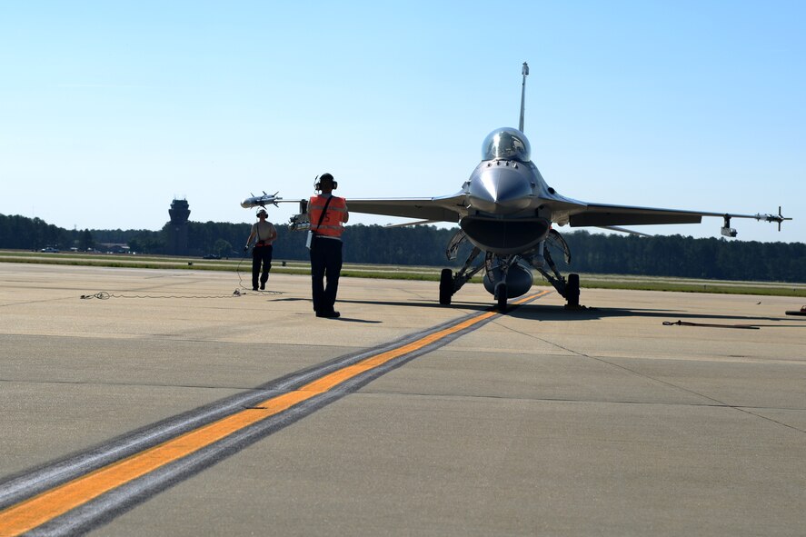 A crew chief and logistics readiness fuel operator taxi a jet in and prepare it to be refueled, Shaw Air Force Base, S.C., May 9, 2013. The hot pits refueling process is practiced to prepare for fast-tempo refueling and to make sure pilots are able to take flight as soon as possible. (U.S. Air Force photo by Airman 1st Class Ashley L. Gardner/Released)
