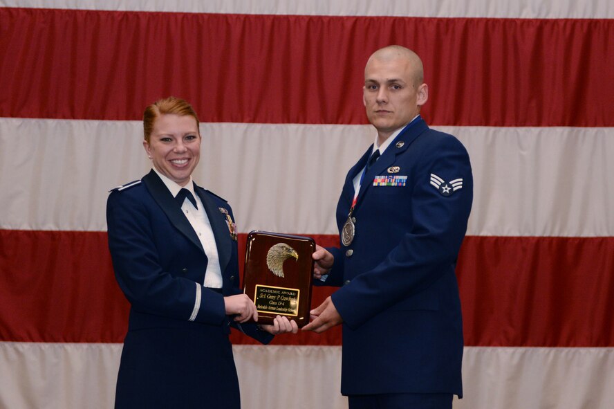 Senior Airman Corey Crawford, 2nd Maintenance Squadron, receives the Academic Award from 1st Lt. Carissa Hoosline, 2nd Force Support Squadron, during the Airman Leadership School Class 13-4 graduation on Barksdale Air Force Base, La., May 9, 2013. (U.S. Air Force photo)