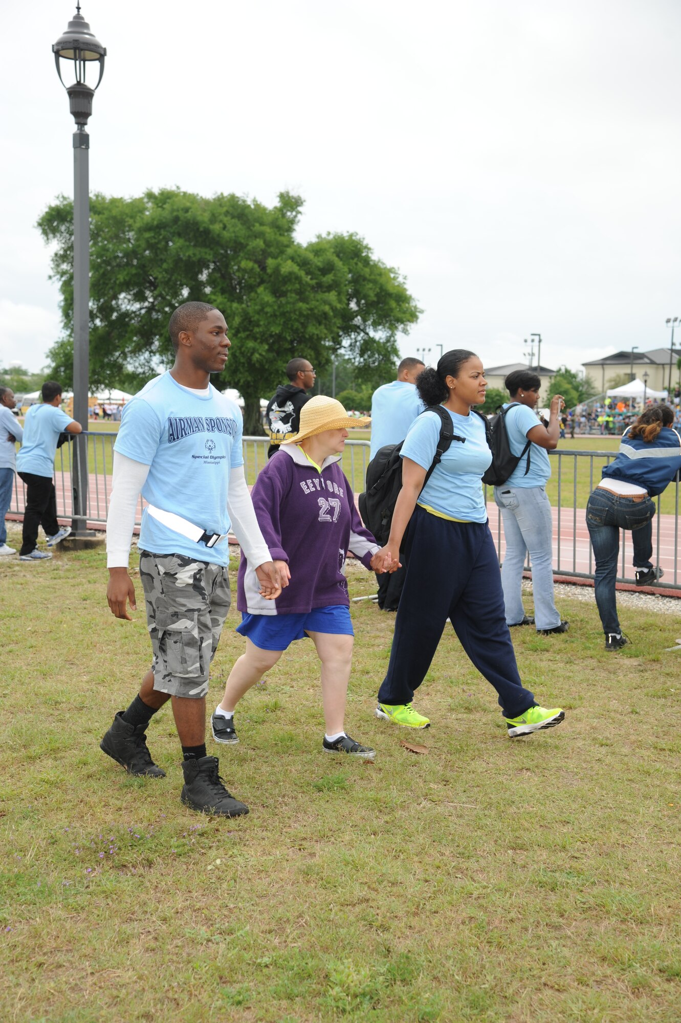 Christy Rawls, athlete, walks hand-in-hand with her sponsors, Airmen 1st Class Cameron Jackson, 334th Training Squadron, and Alessandra Goler, 336th TRS, at the Special Olympics Mississippi Summer Games on May 11, 2013, at Keesler Air Force Base, Miss.  More than 900 athletes and 3,000 volunteers worked together to hold competitions throughout the day.  This is the 27th year Keesler has hosted the state Special Olympics.   (U.S. Air Force photo by Kemberly Groue)