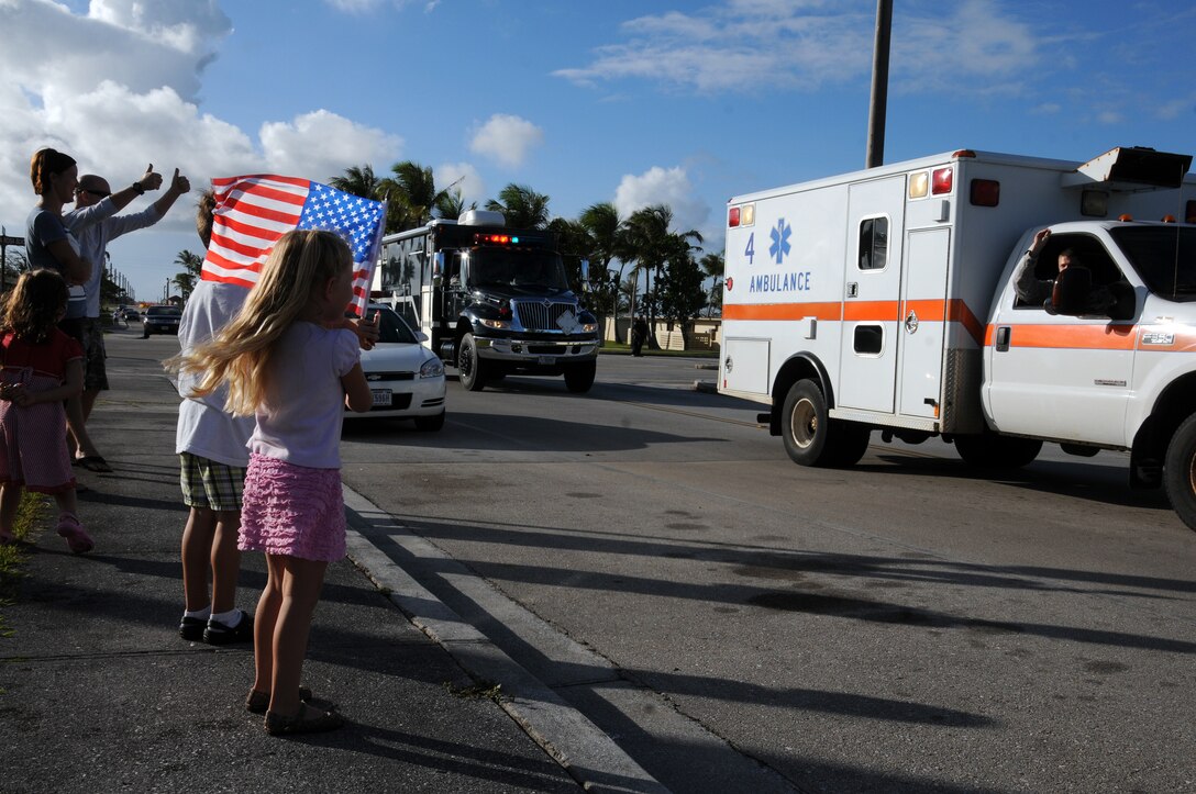 Families watch more than 30 Airmen in 12 emergency services vehicles drive by during the National Police Week parade on Andersen Air Force Base, Guam, May 14, 2013. In 1962, President John F. Kennedy designated May 15 as Peace Officers Memorial Day and the week in which that date falls as National Police Week to recognize law enforcement professionals and their sacrifices. (U.S. Air Force photo by Staff Sgt. Melissa B. White/Released)