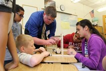 Marine Corps Systems Command engineer Brett Comer helps students prepare sling lengths for his model wooden vehicle during a science, technology, engineering and mathematics, or STEM, event May 9 at Quantico Middle/High School. 