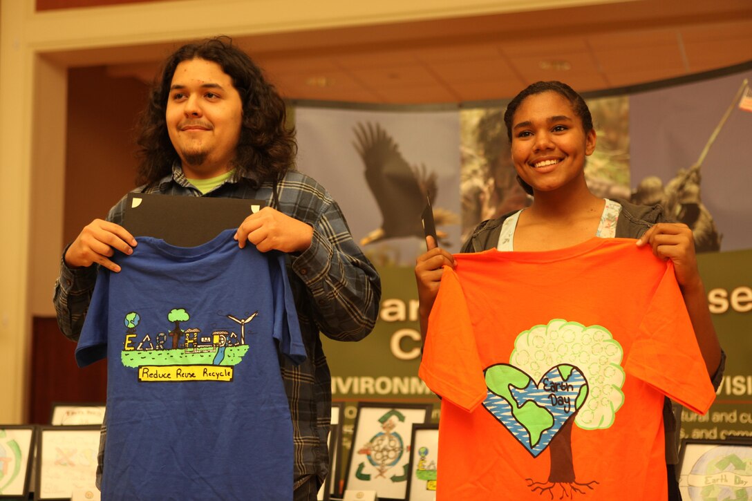 Nicholas Rangel and Alexis May hold t-shirts with their winning designs during the 10th Annual Earth Day Fair and Art Contest at the Marston Pavilion aboard Marine Corps Base Camp Lejeune April 24. The contest received a total of 13 designs. (Photo by Pfc. Justin A. Rodriguez/released)