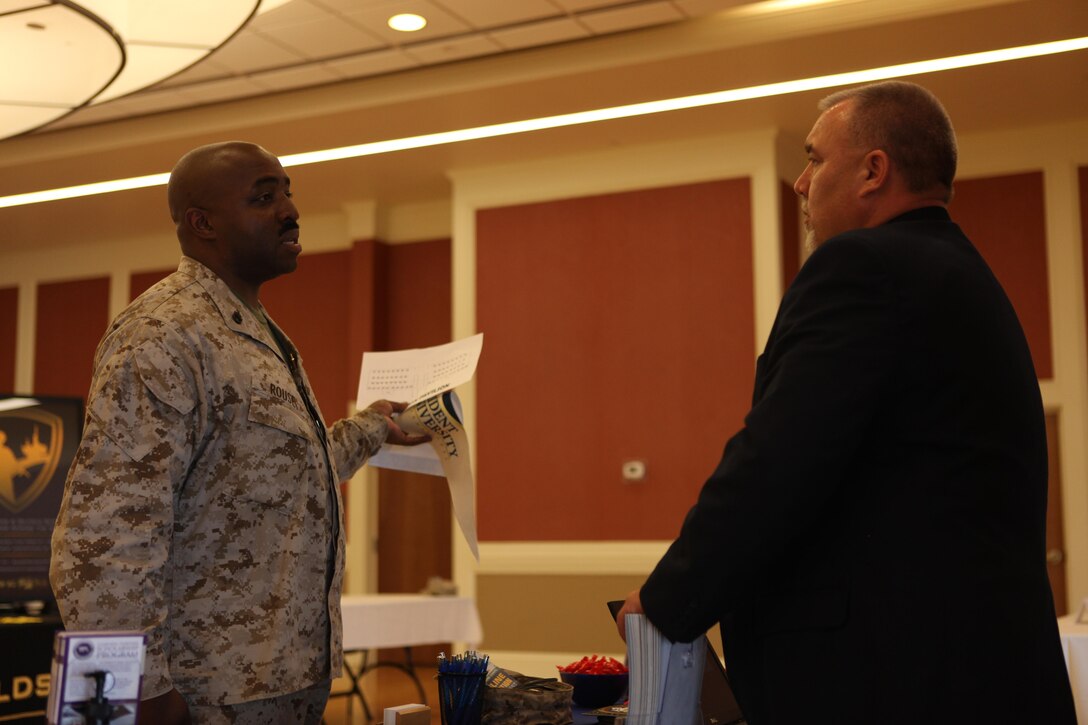 Navy Chief Petty Officer Derrick Rouse, a chief hospital corpsman with Marine Aircraft Group 26 at Marine Corps Air Station New River, speaks with a college representative about opportunities during the Navy at the National Education and Job Fair at the Marston Pavilion aboard Marine Corps Base Camp Lejeune April 18. More than 60 colleges attended. (Photo by Pfc. Justin A. Rodriguez/released)