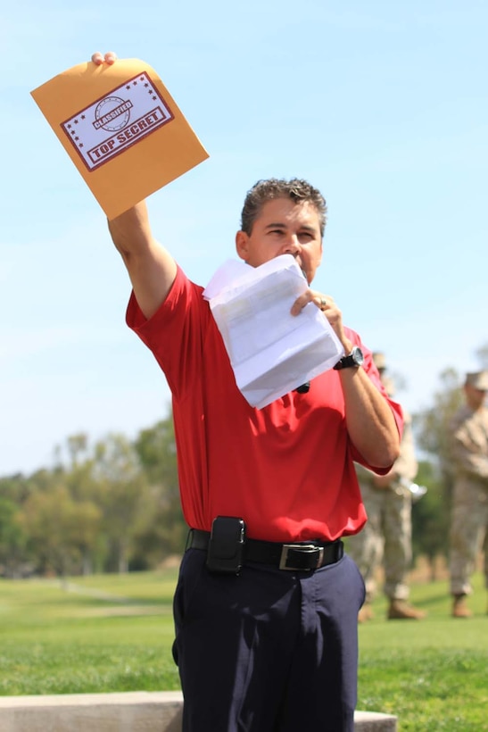 Jody Clor, the general manager of the Marine Memorial Golf Course, holds up an imitation top secret folder containing information regarding the different challenges participants must face during the Commanding General's 2nd Invitational Golf Tournament at the Marine Memorial Golf Course here, May 14, 2013. The tournament provided a unique opportunity for Marines and sailors to network and share experiences with business and community leaders as well as golf industry experts. Each of the 18 holes on the course gave the participants challenges, varying from wearing a flak jacket to playing with alcohol impairment goggles. The intent of the invitational was to highlight facilities aboard the base that are accessible to civilians and provide information about the installation to invited guests.