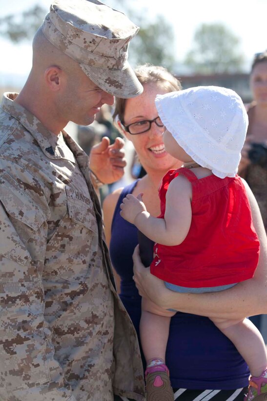 Corporal Jonathan Hunter, an infantryman serving Weapons Company, 3rd Battalion, 5th Marine Regiment, a Dallas native, hugs Joanna, his wife, and their daughter on the parade deck at Camp San Mateo parade deck here, May 13, 2013 Families and friends reunited with their Marines and sailors after an eight-month deployment with the 15th Marine Expeditionary Unit. The MEU deployed Sept 17, 2012, and traveled to Dubai, Jordan, Oman, China, and Hawaii.