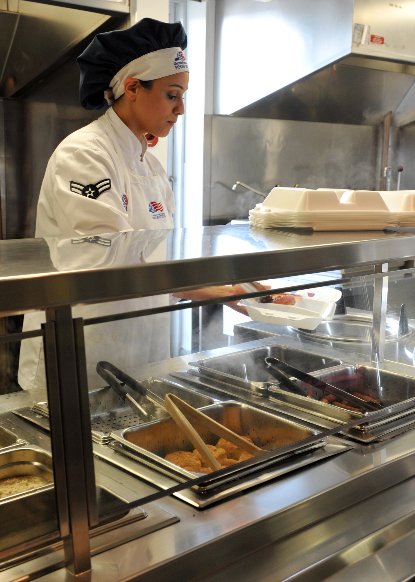 Airman 1st Class Taqla (Tina) Eidson, 509th Force Support Squadron flight kitchen food service specialist, dishes food into a to go container during her shift at the Touch N’ Go In-Flight Kitchen at Whiteman Air Force Base, Mo., April 3, 2013. The squadron’s high standards of professionalism, attitude, and culinary skills led to them being named the 2013 John L. Hennessy Trophy winner. (U.S. Air Force photo by Heidi Hunt/Released)