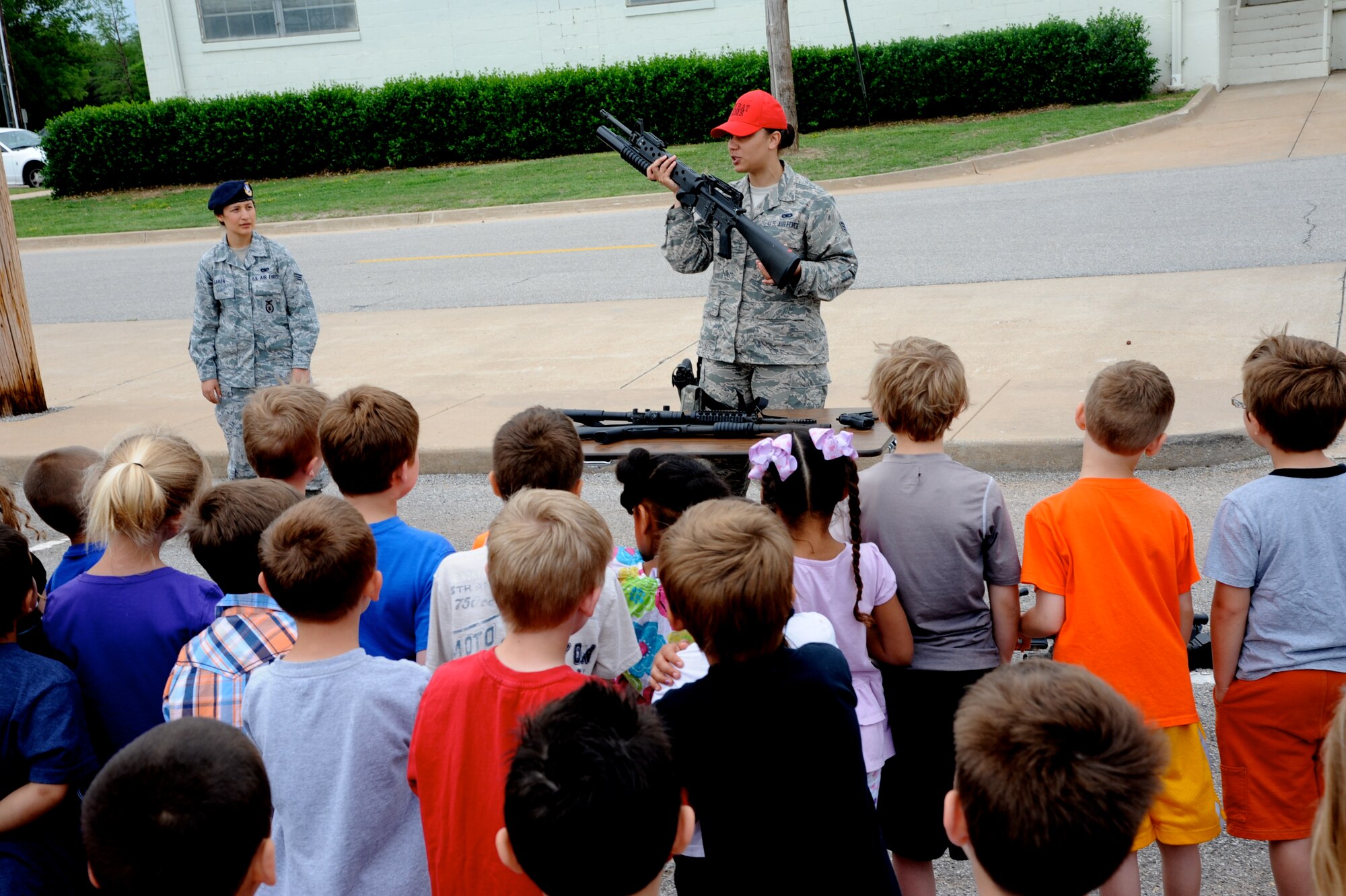Senior Airman Tynisia Hains, with the 71st Security Forces Squadron, explains the ins and outs of the M16 rifle with a grenade launcher attachment to school children, May 15, during National Police Week at Vance Air Force Base, Okla. (U.S. Air Force photo/ Senior Airman Frank Casciotta)