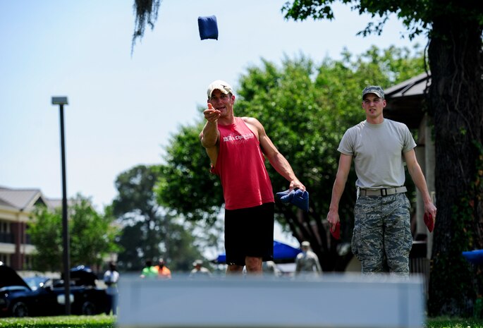 Staff Sgt. Eric Genther (right), 628th Civil Engineer Squadron structures craftsman, watches as Senior Airman Nolan Renfro, 628th CES pest management apprentice, tosses a bean bag during a cornhole game at the Dorm Tailgate Party May 10, 2013, at Joint Base Charleston - Air Base, S.C. The Tailgate Party was designed to strengthen social ties among dorm members and enhance their esprit de corps. The party was sponsored by the Single Airman's Initiative Program and the Air Force Sergeants Association, and included a dirty truck competition, a hot dog eating contest, a basketball tournament and a live DJ. (U.S. Air Force photo/Staff Sgt. Rasheen Douglas)