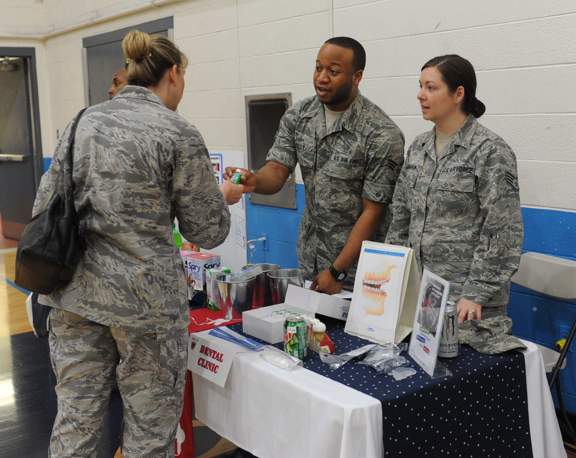 Staff Sgt. Brittany Lanahan and Senior Airman Zarrian Kelly offer dental health information to a patron during the community health fair at James Gym May 10.  The health fair was part of nurses/medical technician’s week, which recognizes the work that these professionals do for the clinic patients.  (U.S. Air Force photo/Staff Sgt. Maria Bowman)
