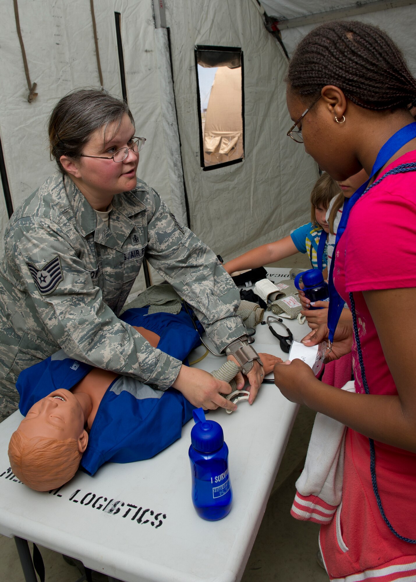 Tech. Sgt. Cheryl Chowning, 49th Medical Operations Squadron family health NCO in charge, demonstrates how to apply a pressure bandage to a wound for “deployers” at “Bearghanistan” during Operation Kids Investigating Deployment at Holloman Air Force Base, N.M., May 13. Operation K.I.D. gave the “deployers” an inside look at what their parents go through when called to deploy. (U.S. Air Force photo by Senior Airman Kasey Close/Released)