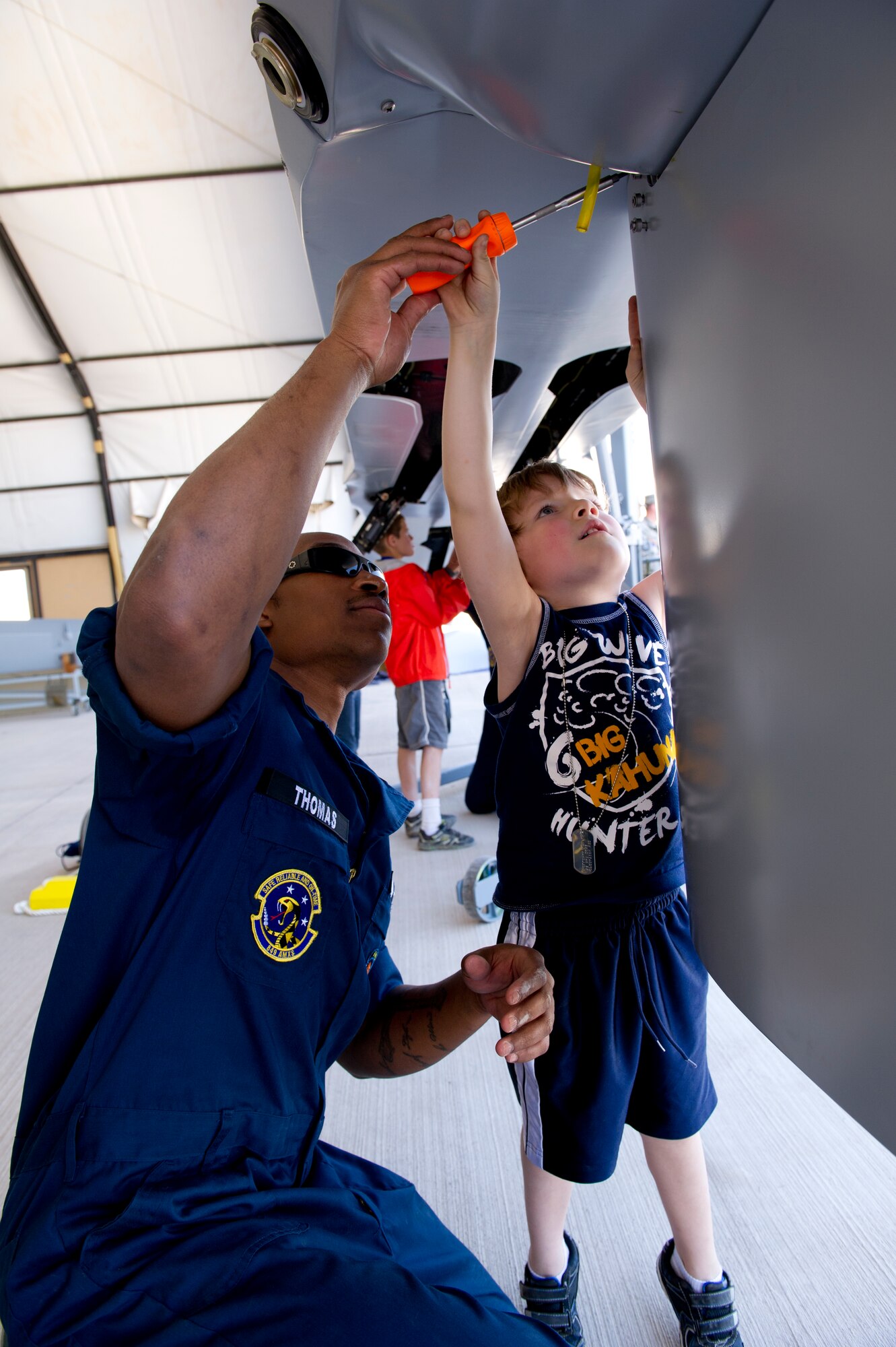 Staff Sgt. Terelle Thomas, 6th Aircraft Maintenance Unit MQ-1 Predator crew chief, assists a “deployer” in attaching a fin to an MQ-1 at “Bearghanistan” during Operation Kids Investigating Deployment at Holloman Air Force Base, N.M., May 13. The “deployers” experienced a recall, deployment line, deployment to “Bearghanistan,” and welcome home. (U.S. Air Force photo by Senior Airman Kasey Close/Released)
