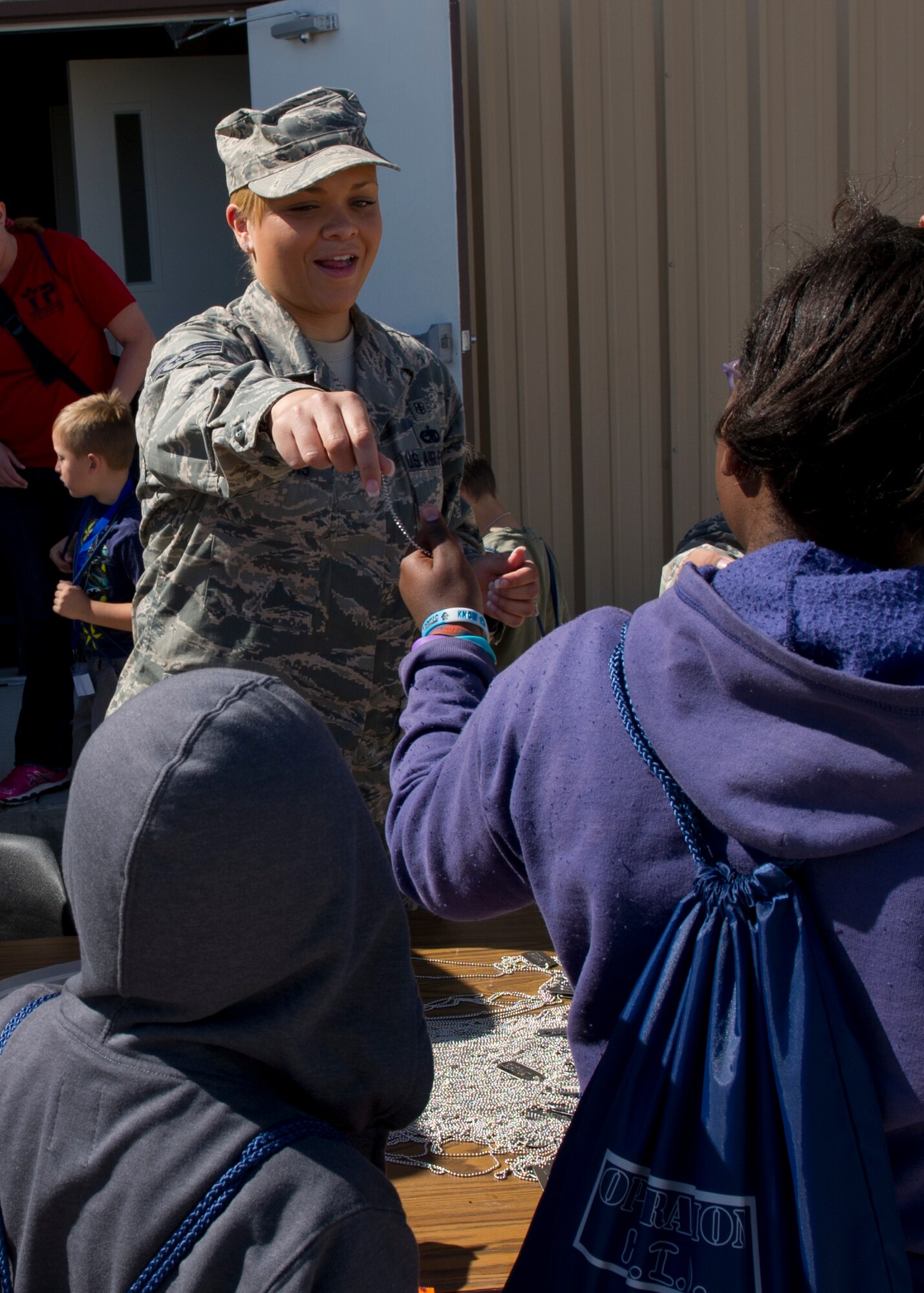 Staff Sgt. Stephanie Hagans, 49th Aerospace Medical Squadron public health technician, gives dog tags to the “deployers” at the deployment processing line during Operation Kids Investigating Deployment at Holloman Air Force Base, N.M., May 13. Operation K.I.D. gave the “deployers” an inside look at what their parents go through when called to deploy. (U.S. Air Force photo by Senior Airman Kasey Close/Released)