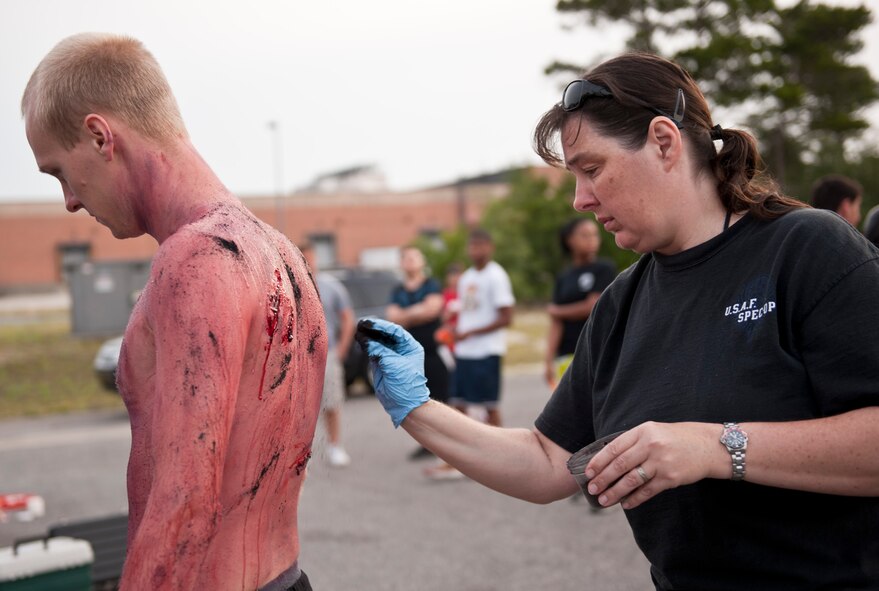 Master Sgt. Michele Swartz, medic for the Air Force Special Operations Command, applies make-up to an Airman playing the role of a mock victim with multiple cuts and wounds during Chemical, Biological, Radiological, Nuclear and Explosive response training on Hurlburt Field, Fla., May 10, 2013. The scenario involved an early morning mock car-bombing at the base car wash with 17 victims suffering from possible mock injuries. (U.S. Air Force photo by Senior Airman Krystal M. Garrett)