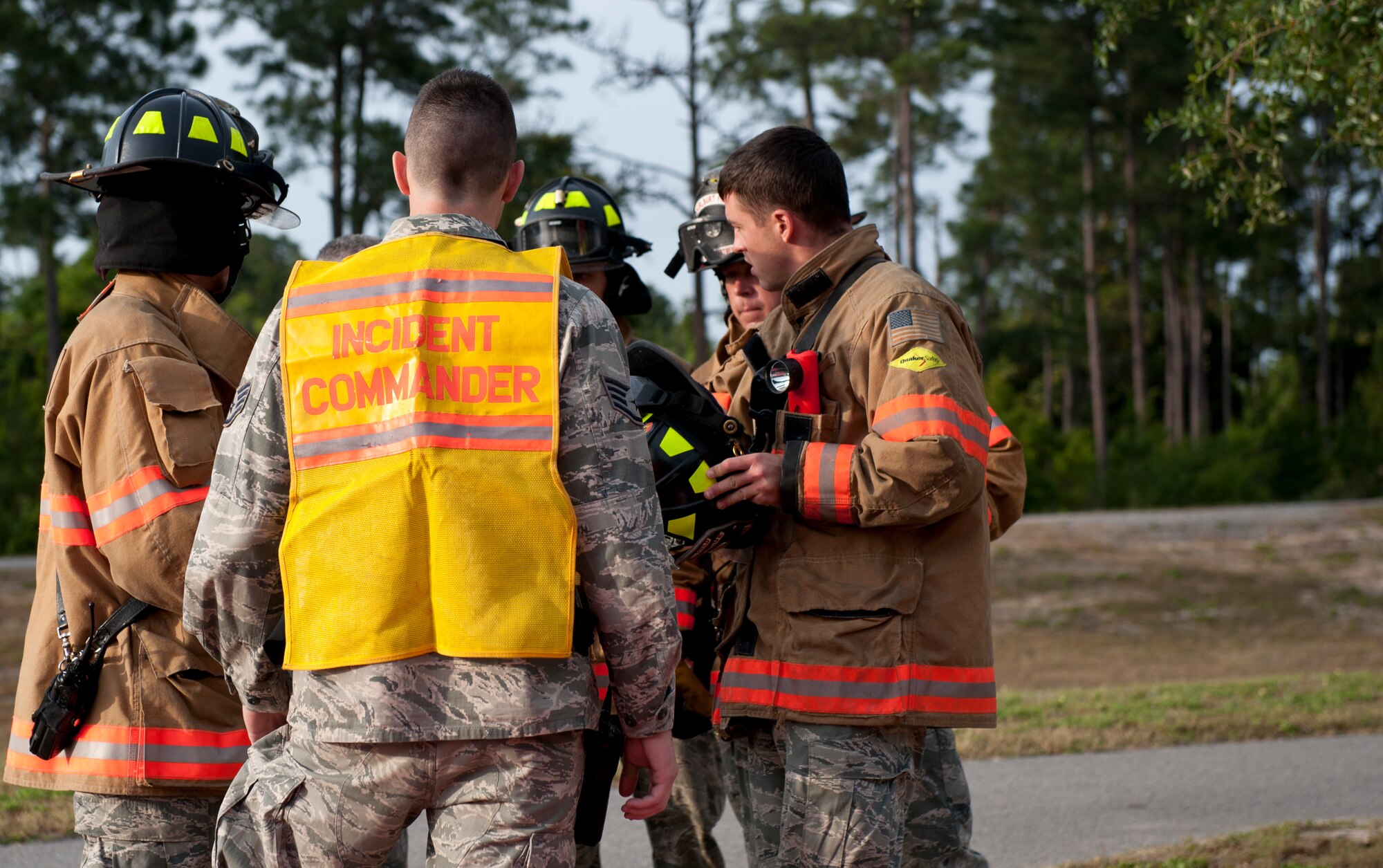 The incident commander and firefighters from the 1st Special Operations Civil Engineer Squadron discuss details about the Chemical, Biological, Radiological, Nuclear and Explosive response training held on Hurlburt Field, Fla., May 10, 2013. Fire department personnel assessed and placed the injured on tarps, depending on their injuries, and quickly provided appropriate treatment to each casualty once medical personnel arrived. (U.S. Air Force photo by Senior Airman Krystal M. Garrett)