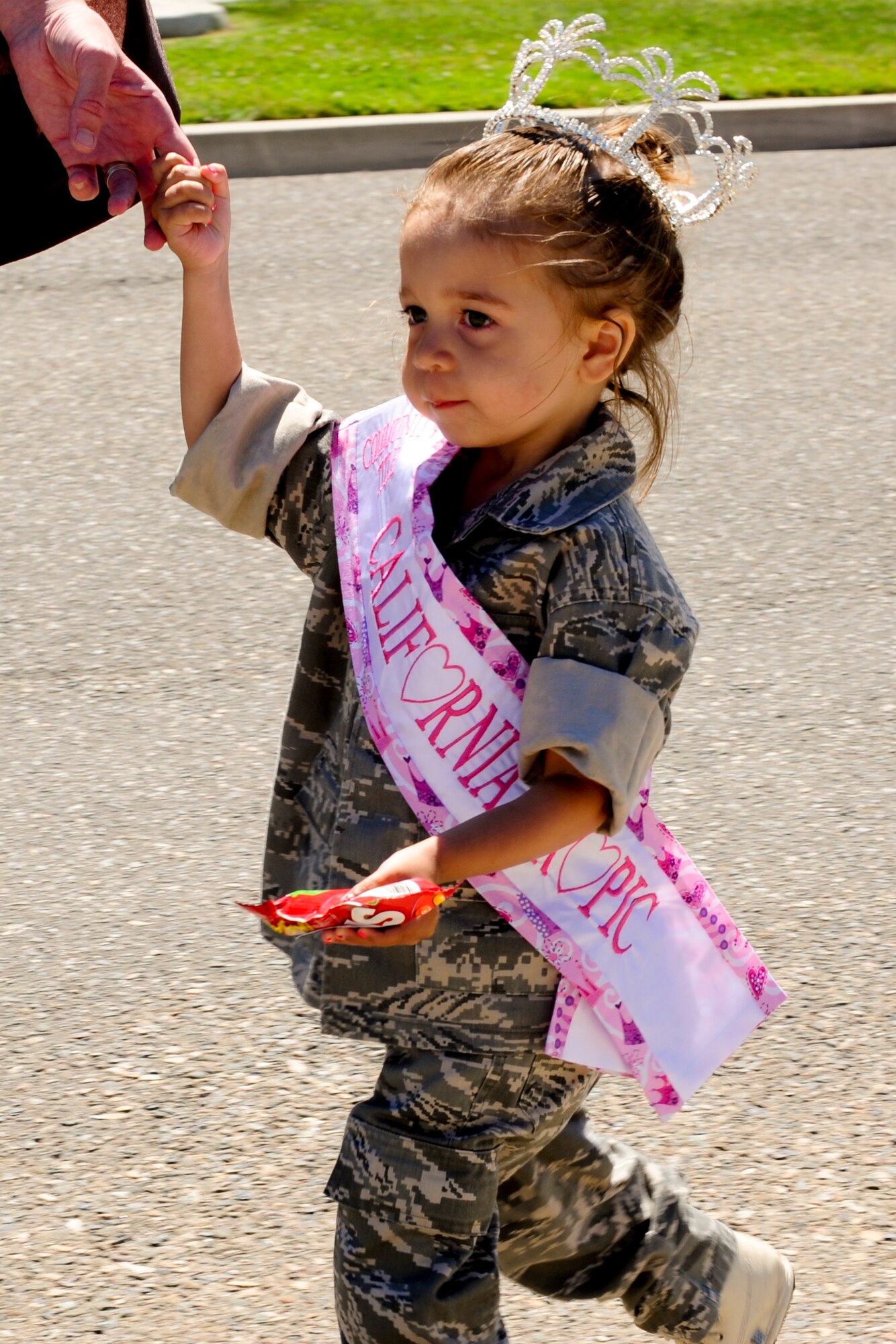 VANDENBERG AIR FORCE BASE, Calif. – A little princess dressed in military clothing hands out candy during Team V’s National Police Week parade here Monday, May 13, 2013. The 30th Security Forces Squadron hosted a parade on base for all military, civilians and their families as part of their National Police Week celebration. The event, which included Team V defenders and local law enforcement agencies, showcased many different types of vehicles and animals law enforcement agencies use. (U.S. Air Force photo/Airman Yvonne Morales) 