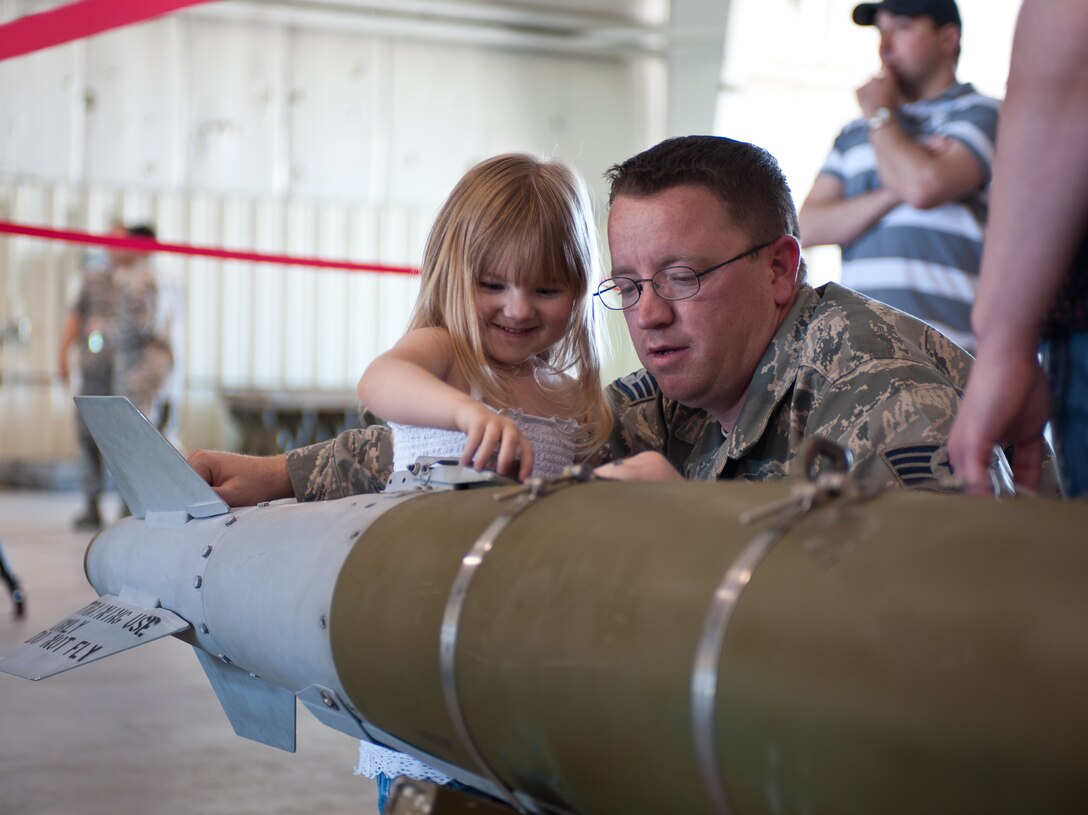 Staff Sgt. Nick Richards, 28th Munitions Squadron conventional maintenance support NCO in charge, shows his daughter, Jazlynn, an inert munition and explains his job to her during Spouse Appreciation Day at Ellsworth Air Force Base, S.D., May 10, 2013. In addition to numerous activities around the base many agencies arranged displays and entertainment specifically for families of Airmen in their units. (U.S. Air Force photo by Airman 1st Class Alystria Maurer/Released)
