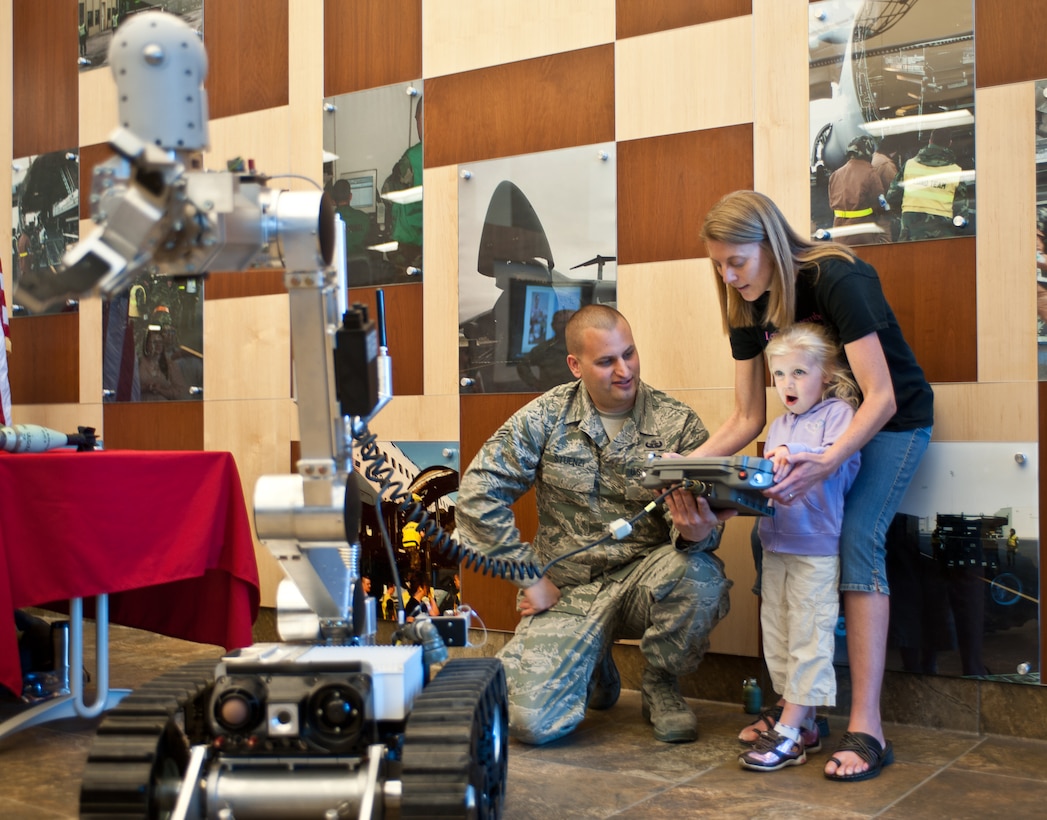 Staff Sgt. Michael Stuenzi, 28th Civil Engineer Squadron explosive ordnance disposal technician, assists Julie Hutchinson, wife of Lt. Col. Barry Hutchinson, 28th Bomb Wing chief of plans, and their daughter Ruth, in operating an EOD robot during Spouse Appreciation Day at Ellsworth Air Force Base, S.D., May 10, 2013. The EOD display provided families with the opportunity to operate the robot, wear an advanced bomb suit, and see what types of munitions the 28th CES EOD team is capable of disposing. (U.S. Air Force photo by Airman 1st Class Alystria Maurer/Released)