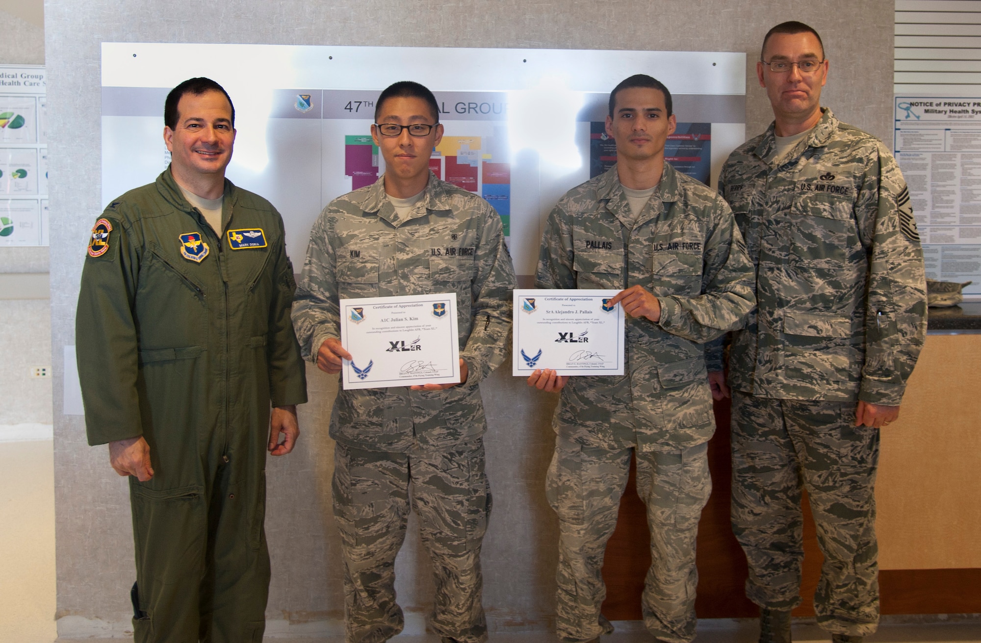 Airman 1st Class Julian Kim, center left, and Senior Airman Alejandro Pallais, 47th Medical Operations Squadron bioenvironmental engineering technicians, poses with Col. Mark Doria, 47th Flying Training Wing commander, and Chief Master Sgt. Garry Berry, 47th FTW command chief, after being presented the XLer of the week award at Laughlin Air Force Base, Texas, May 7, 2013. The XLer is a weekly award chosen by wing leadership and given to those who consistently make outstanding contributions to Laughlin and their unit. (U.S. Air Force photo/Airman 1st Class John D. Partlow)
