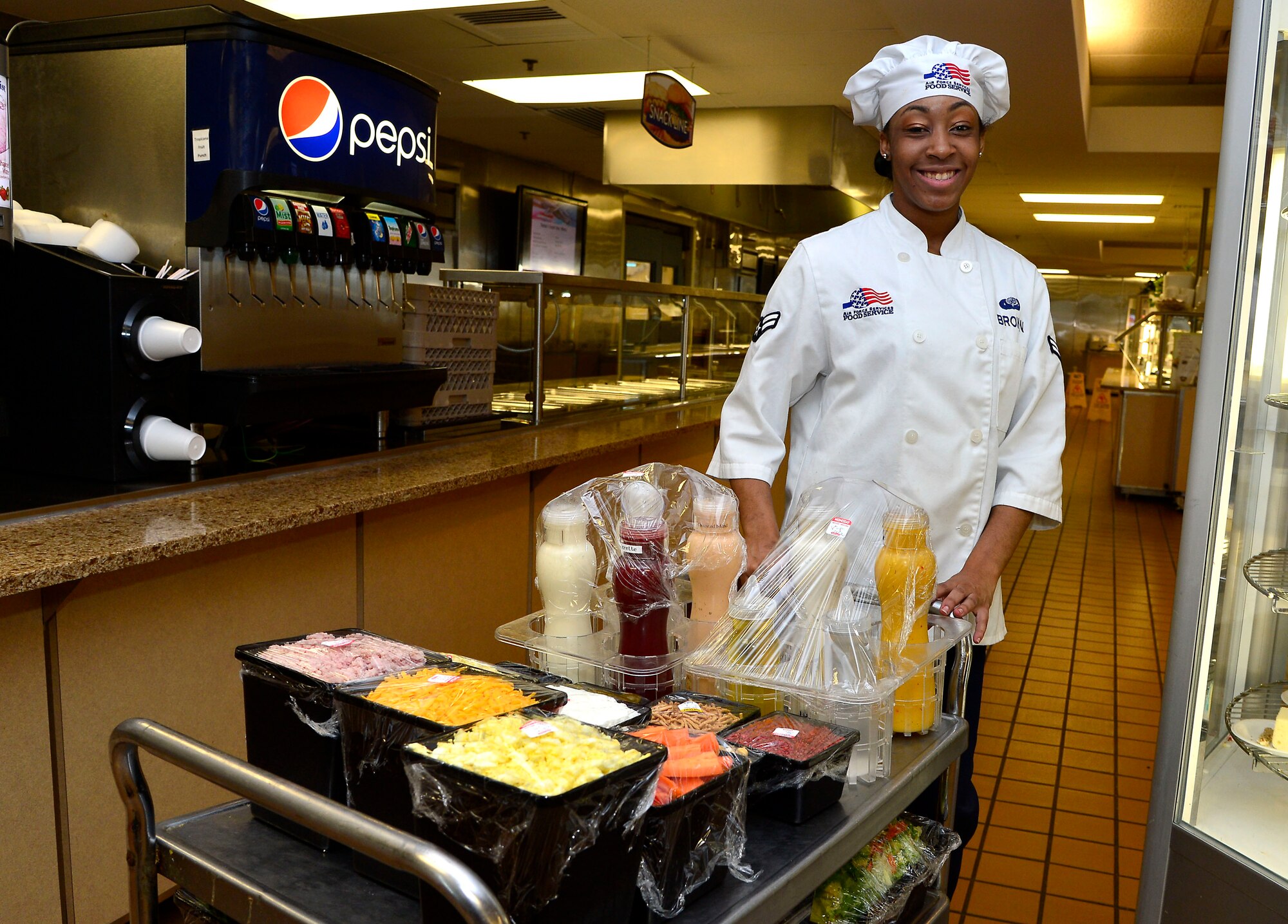 Airman 1st Class Ashanti Brown, 436th Force Support Squadron baker, poses in front of the salad bar at the Patterson Dining Facility on Dover Air Force Base, Del., May 8. The DFAC serves about 600-700 Airmen a day. (U.S. Air Force photo/David S. Tucker)