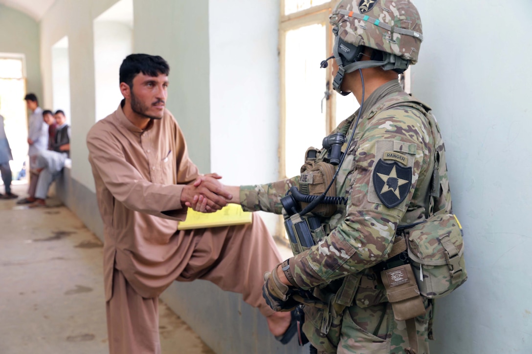 U.S. Army 1st Lt. Robert Wolfe, right, shakes hands with a high school student during a key leader engagement at Aboonaser Farahi high school in Farah City, Afghanistan, May 13, 2013. Wolfe, a platoon leader, is assigned to Provincial Reconstruction Team Farah.