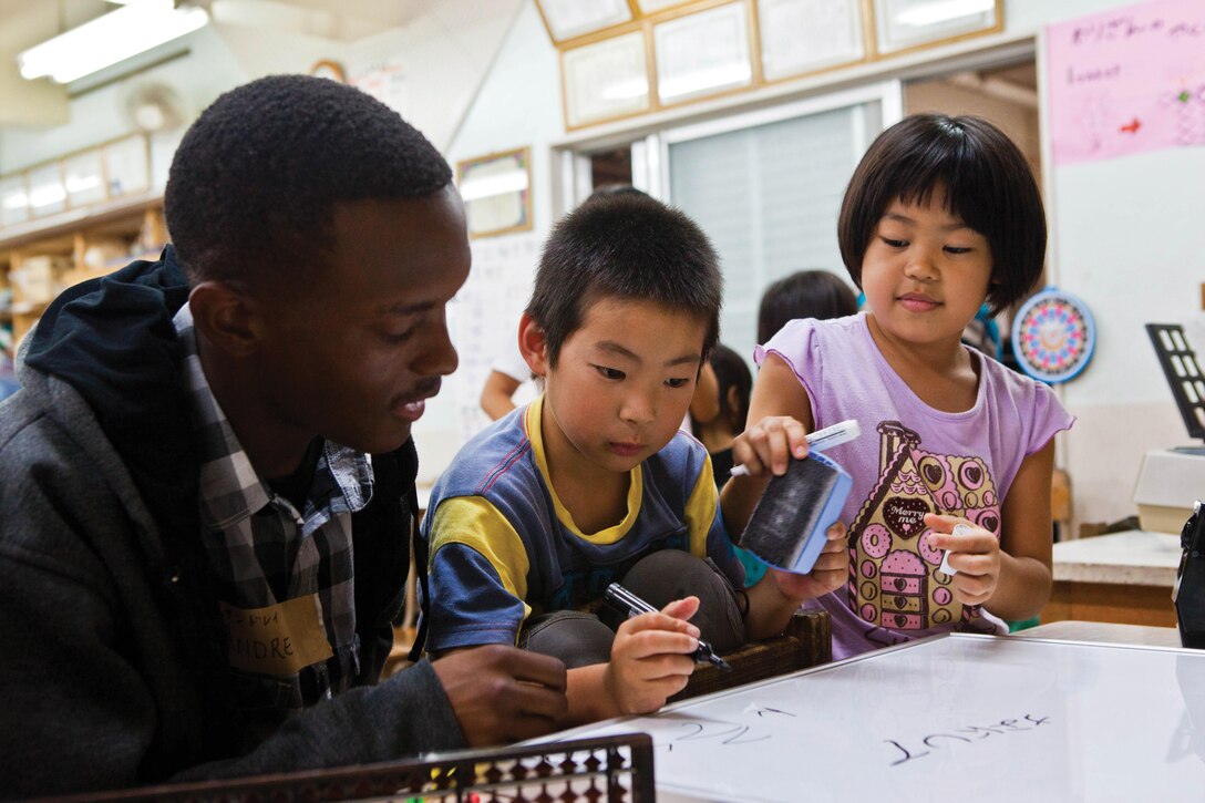 Pfc. Andre D. Edwards, left, draws with children during a visit at the Himawari Gakudo Day Care Center May 11.  Marines and sailors from Camp Schwab visited the center to play games and interact with the children. Edwards is a motor vehicle operator with Headquarters and Service Company, 3rd Battalion, 6th Marine Regiment, which is currently assigned to 4th Marine Regiment, 3rd Marine Division, III Marine Expeditionary Force, under the unit deployment program. Photo by Pfc. Kasey Peacock