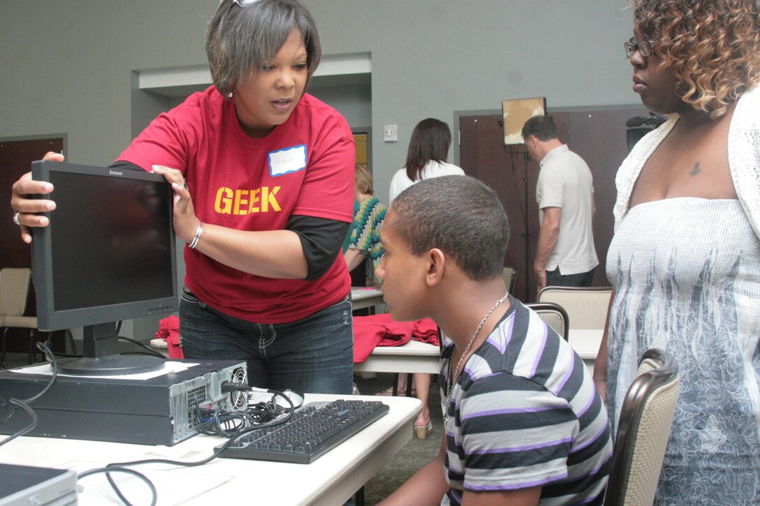Sharnee Moody’s son, 12, watches as a volunteer teaches him how to use his new computer May 11 at Millers Landing during the computer “Give-a-Thon.” The computers were awarded to students by Kramden and Lenovo institutions to help students who did not have access to a computer at home. 