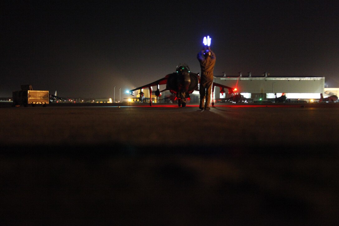A VMA-542 plane captain guides an AV-8B Harrier in for parking after completing a training mission the night of May 9.