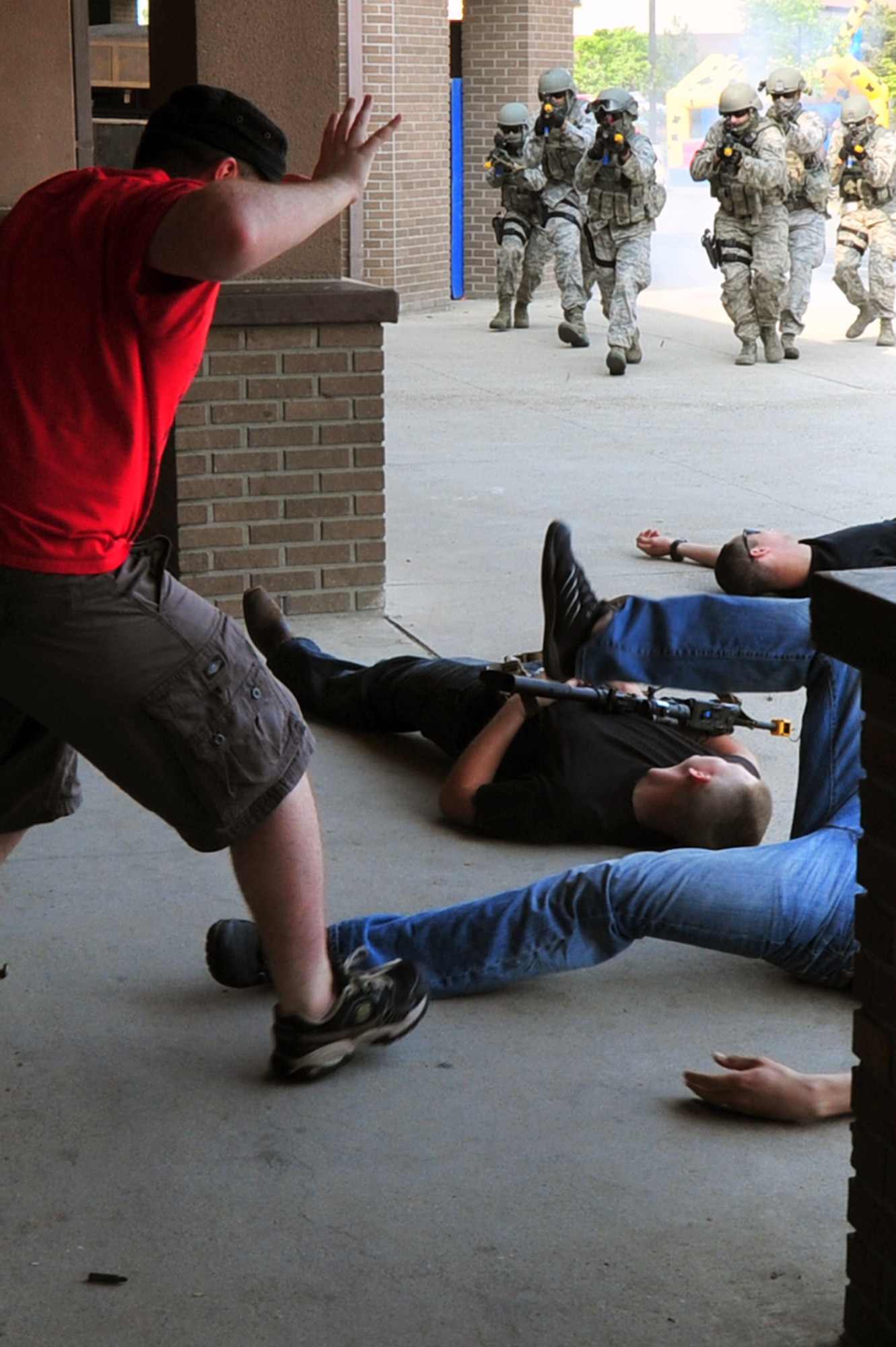 Senior Airman Taylor Crowe, 303rd Intelligence Squadron threat analyst and demonstration hostage, gets on the ground as the Quick Reaction Team members from the 51st Security Forces Squadron subdue bank robbers in a demonstration at the Base Exchange on Osan Air Base, Republic of Korea, May 15, 2013. The QRT is a specialized group of security forces members who are trained to respond to high-risk situations. (U.S. Air Force photo/Senior Airman Alexis Siekert)