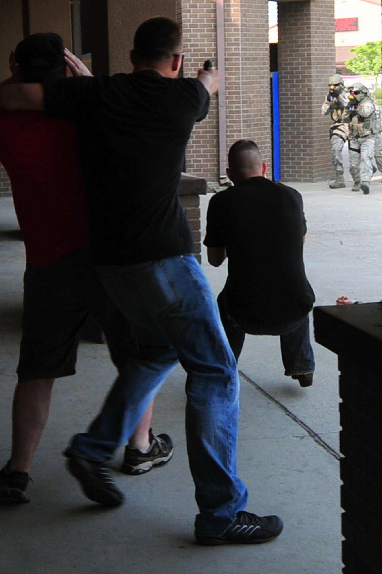 Staff Sgt Christopher Johanson, left, 51st Security Forces Squadron defender acting as a bank robber, shoots at approaching Quick Reaction Team members in a demonstration at the Base Exchange on Osan Air Base, Republic of Korea, May 15, 2013. During the demo, the QRT was able to eliminate the threat and save the hostage. (U.S. Air Force photo/Senior Airman Alexis Siekert)