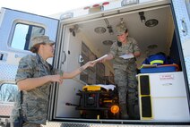 (Right) Airman 1st Class Alexys Ramkishun, 319th Medical Operation Squadron emergency medical technician, hands information pamphlets to her fellow paramedic, Airman 1st Class Alexandria McGuire, outside an ambulance used as a static display May 7, 2013, on Grand Forks Air Force Base, N.D. The static display was one of the items featured during the second of five days designated for this year’s Nurse-Tech Week. (U.S. Air Force photo/Staff Sgt. Luis Loza Gutierrez)
