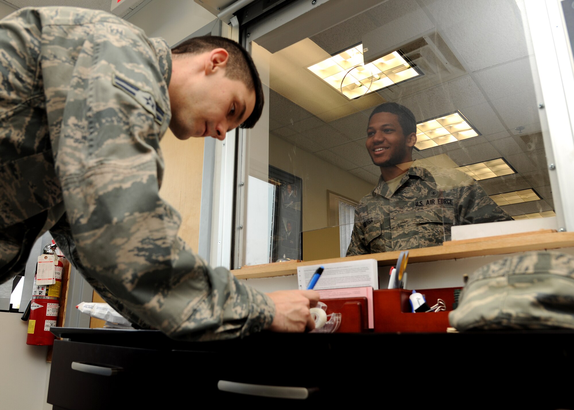 (From left) Airman 1st Class Kyle Elbie, 319th Communications Squadron official mail technician, signs for a package from Airman 1st Class Steve Seltzer III, 319th Medical Group, on May 13, 2013, on Grand Forks Air Force Base, N.D. The Official Mail Center handled approximately 22,000 pounds of parcel in 2012. (U.S. Air Force photo/Airman 1st Class Ashley Nicole Taylor)  