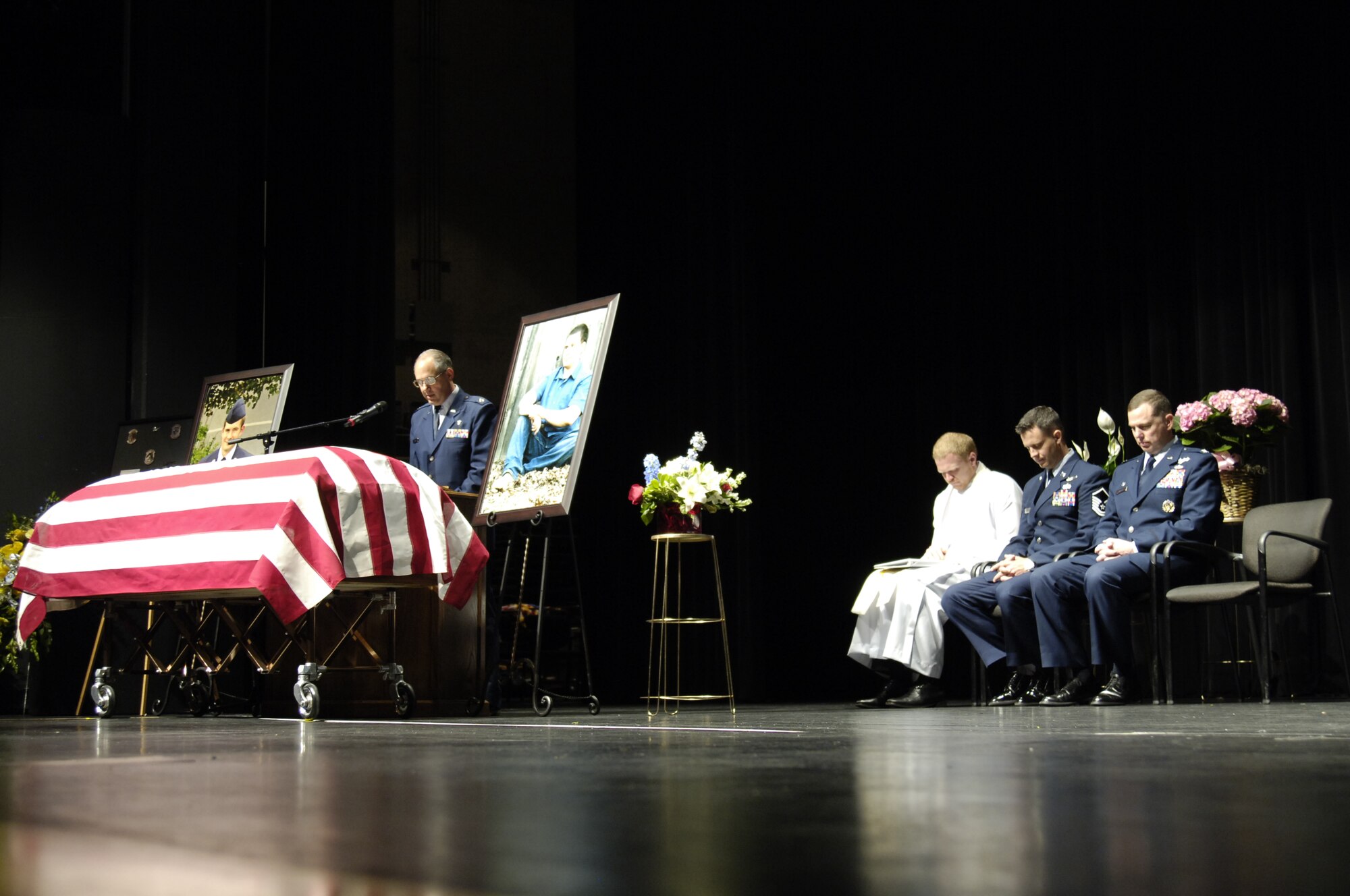 Above, Chaplain (Capt.) Kraig Smith with the 72nd Air Base Wing Chaplain Corps at Tinker Air Force Base provides the opening prayer during a memorial service for Staff Sgt. Daniel Fannin. More than 1,700 people packed the Rose State College Performing Arts Theater on Monday for a memorial service for the former sensor operator assigned to the 552nd Operations Support Squadron, who was killed April 27 along with three other Airmen in a plane crash near Kandahar Airfield in southern Afghanistan. Seated on the stage are, from left, Pastor Craig Born, Gethsemane Lutheran Church; Master Sgt. Christopher Charpentier, who served previously with Sergeant Fannin in the 960th Airborne Air Control Squadron at Tinker; and Col. Greg Guillot, commander, 552nd Air Control Wing. Sergeant Fannin, 30, originally of Morehead, Ky., is survived by his wife, Sonya, of Oklahoma City. The couple has no children. (Air Force photo by Darren D. Heusel)