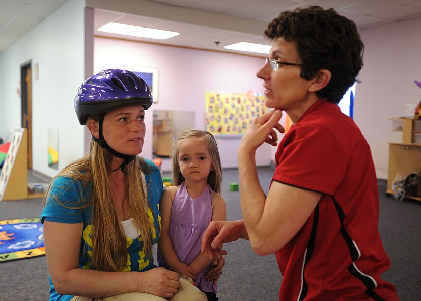 Heather Rodocker, left, and 2-year-old Jaylynn Rodocker, listen as Patty Olsen, Safe Kids Grand Forks sports coordinator, tells them how to properly fit and adjust the chin strap on a bike helmet on May 14, 2013, on Grand Forks Air Force Base, N.D. Safe Kids is a national network of organizations working to prevent unintentional childhood injuries.  (U.S. Air Force Photo/ Airman 1st Class Xavier Navarro)