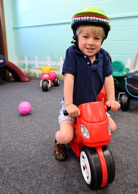 Jackson Jones, 3, shows off his helmet while riding a toy motorcycle on May 14, 2013, on Grand Forks Air Force Base, N.D. Personnel from Safe Kids Grand Forks visited the base to help teach parents and youth how to properly wear bike helmets. The event directly supports the Air Force's service-wide safety programs that strongly focus on keeping Airmen and their families safe. (U.S. Air Force photo/Airman 1st Class Xavier Navarro)