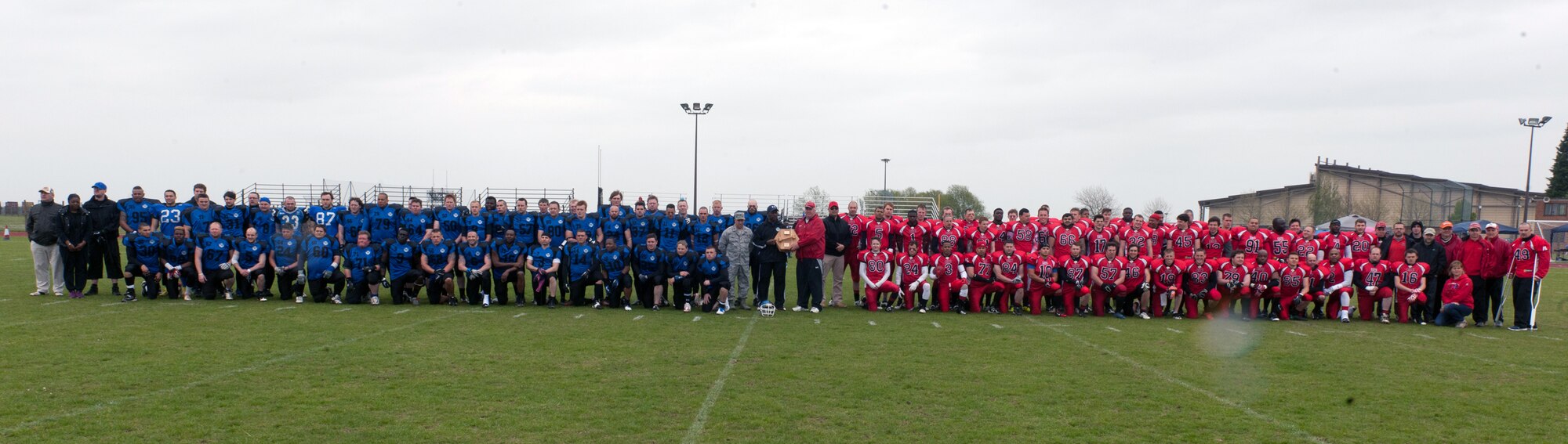 RAF ALCONBURY, United Kingdom – Members of the Peterborough Saxons and Cambridgeshire Cats stand at midfield before kickoff of the first ever Bob "The Dog" Shaw Classic May 12 at the RAF Alconbury football field. These two teams have a history of playing each other for years and consider each other rivals. Both teams also have military personnel from RAF Alconbury, RAF Molesworth, RAF Mildenhall and RAF Lakenheath playing alongside British players. Coach Bob Shaw was a part of both teams as an offensive line coach for both the Saxons and Cats, and was the head coach for the Cats. The game was scheduled to show support for Shaw’s battle with cancer, however Shaw lost the battle the morning of the game. (U.S. Air Force photo by Staff Sgt. Brian Stives)