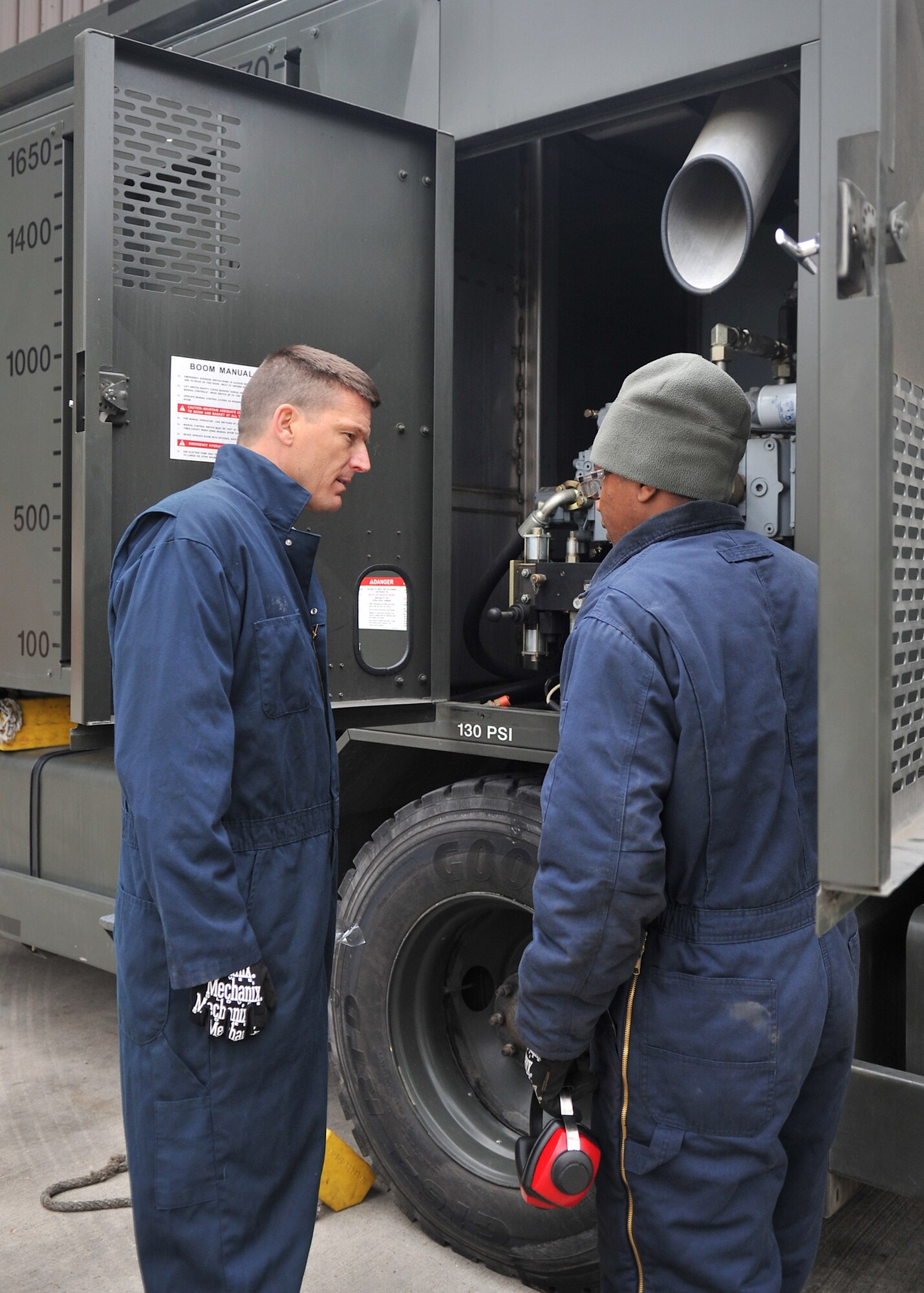 From right, Senior Airman Peter Mwangi, 100th Logistics Readiness Squadron vehicle and vehicular equipment mechanic from Las Vegas, explains the basic features and operations of a global deicer to Chief Master Sgt. Tracy Jones, 100th Air Refueling Wing command chief, during a visit to the 100th LRS Special Purpose shop May 15, 2013, on RAF Mildenhall, England. As part of the base’s “dirty jobs” program, Jones assisted with the inspection of the vehicle. (U.S. Air Force photo by Senior Airman Jerilyn Quintanilla/Released)