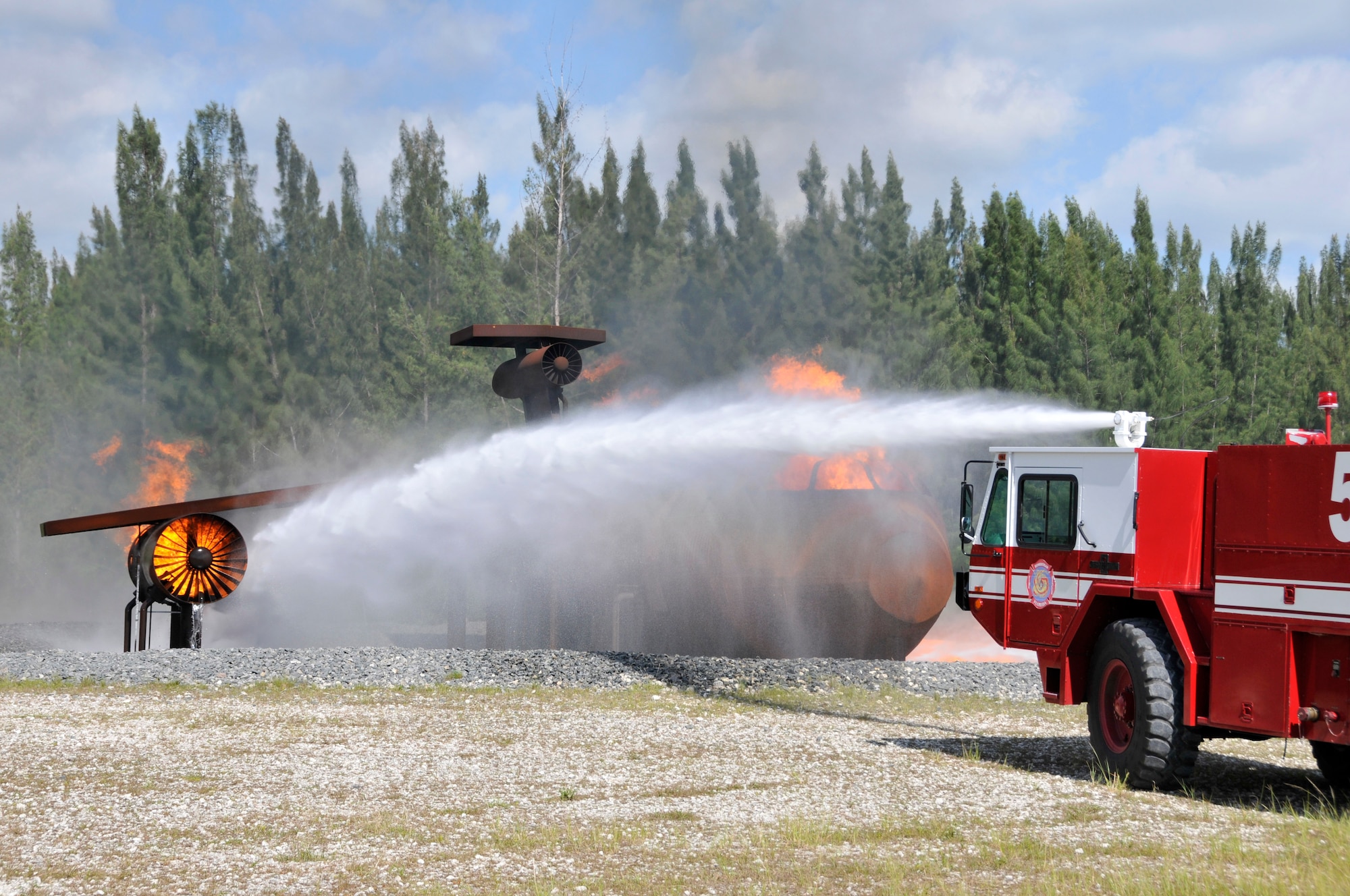 A P-19 fire truck from Homestead Air Reserve Base, Fla., fires water from its roof turret at a mock aircraft during aircraft live fire training at Homestead ARB May 15. Fires can heat up the mock aircraft to approximately 1,200 degrees. The aircraft live fire training consists of responding to the fire, setting up on the aircraft, deploying hose lines, and attacking and extinguishing the fire. (U.S. Air Force photo/Senior Airman Nicholas Caceres)