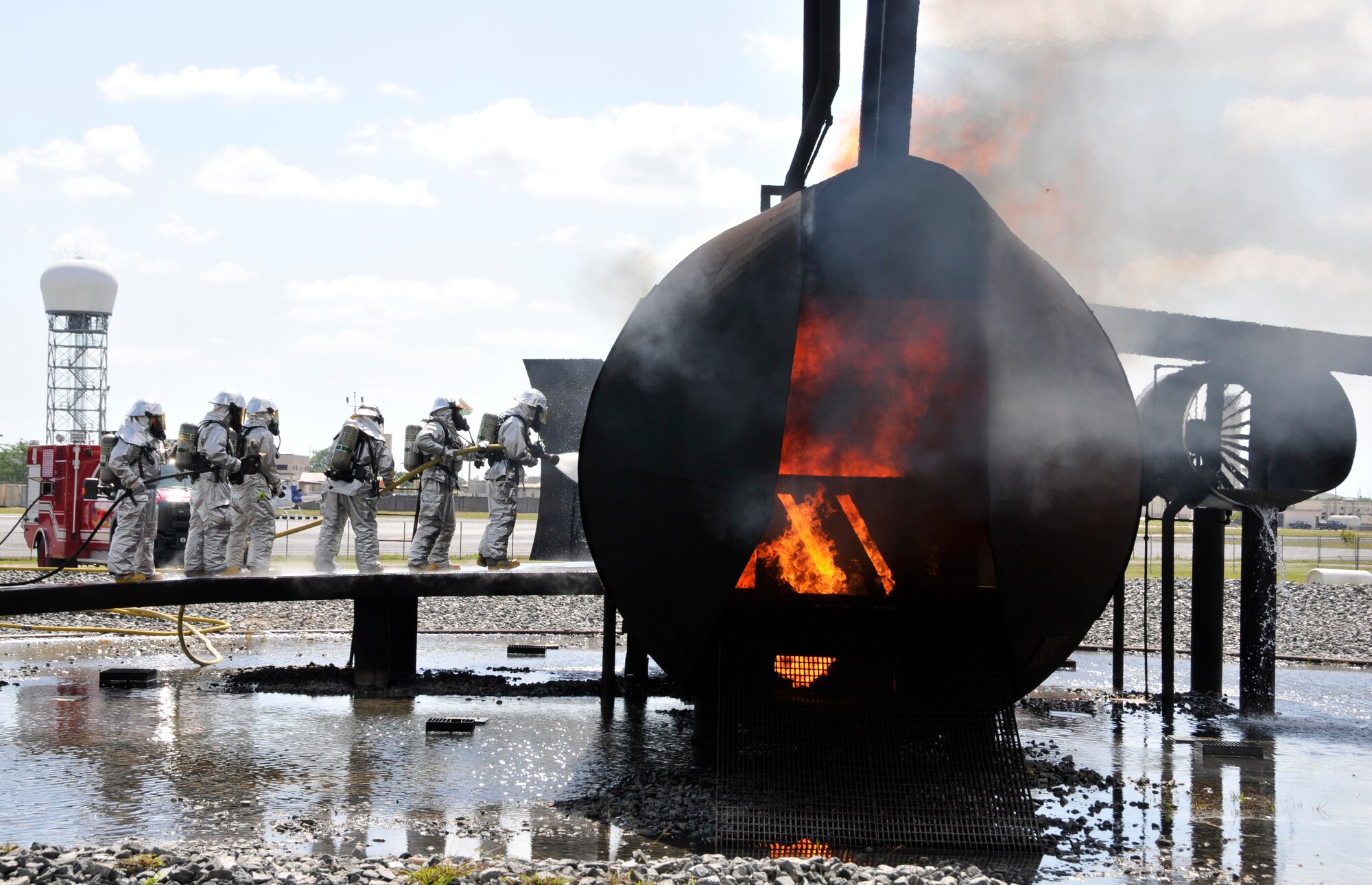 Members of Homestead Air Reserve Base, Fla.’s Fire Department enter the burning fuselage of a mock aircraft during aircraft live fire training at Homestead ARB May 15. Fires can heat up the mock aircraft to approximately 1,200 degrees. The aircraft live fire training consists of responding to the fire, setting up on the aircraft, deploying hose lines, and attacking and extinguishing the fire. (U.S. Air Force photo/Senior Airman Nicholas Caceres)